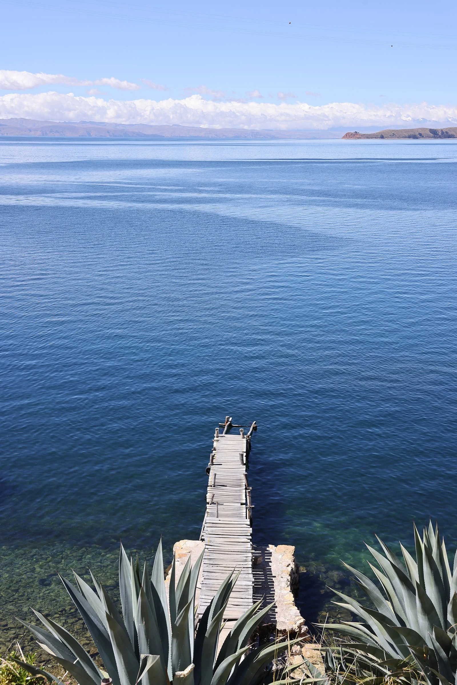 En lång brygga som går ut i Titicacasjöns blå vatten, från ön Isla del Sol i Bolivia