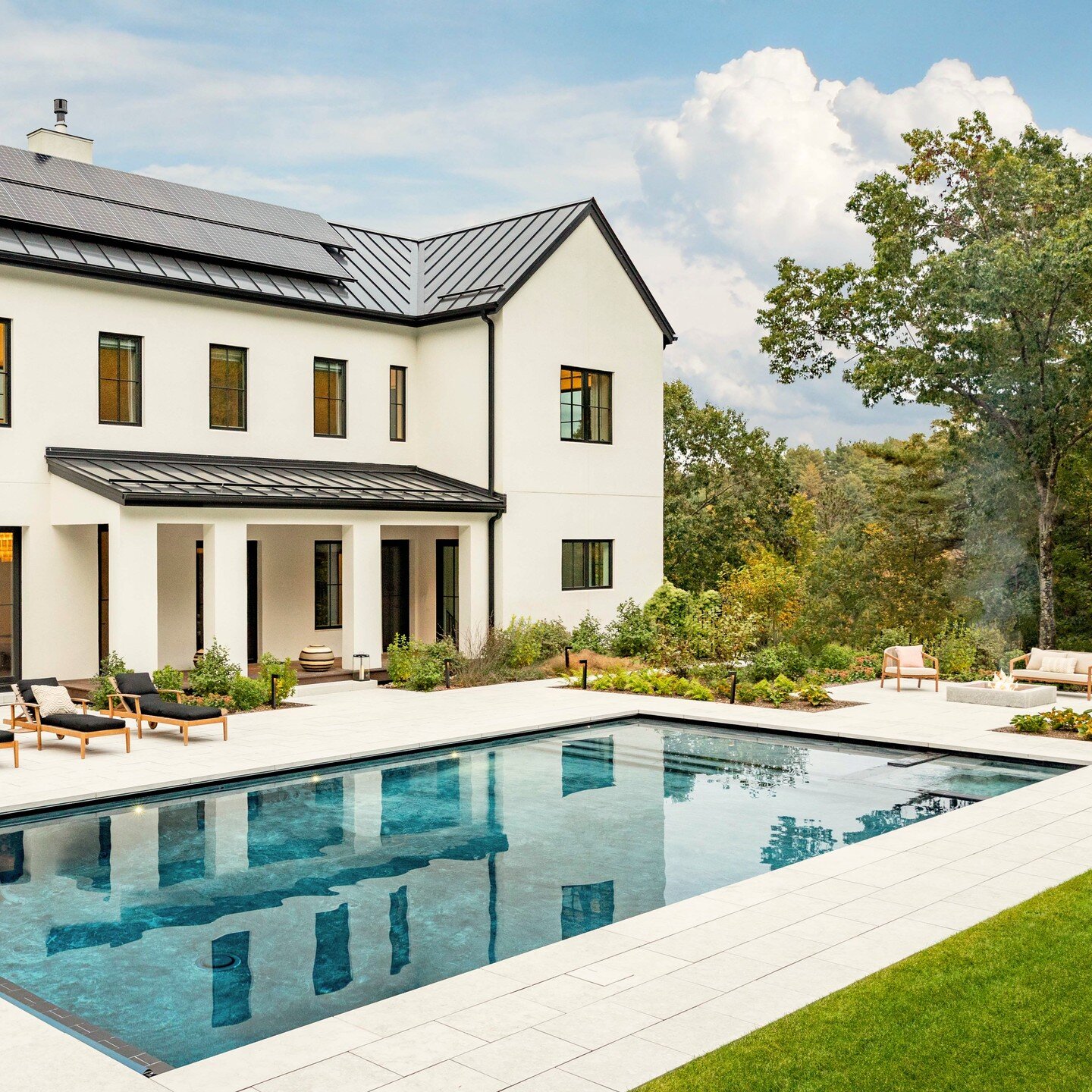 The limestone terrace and granite fire pit at this #modernfarmhouse is a great family space for daytime splashing, evening s'mores, and nighttime cocktails!