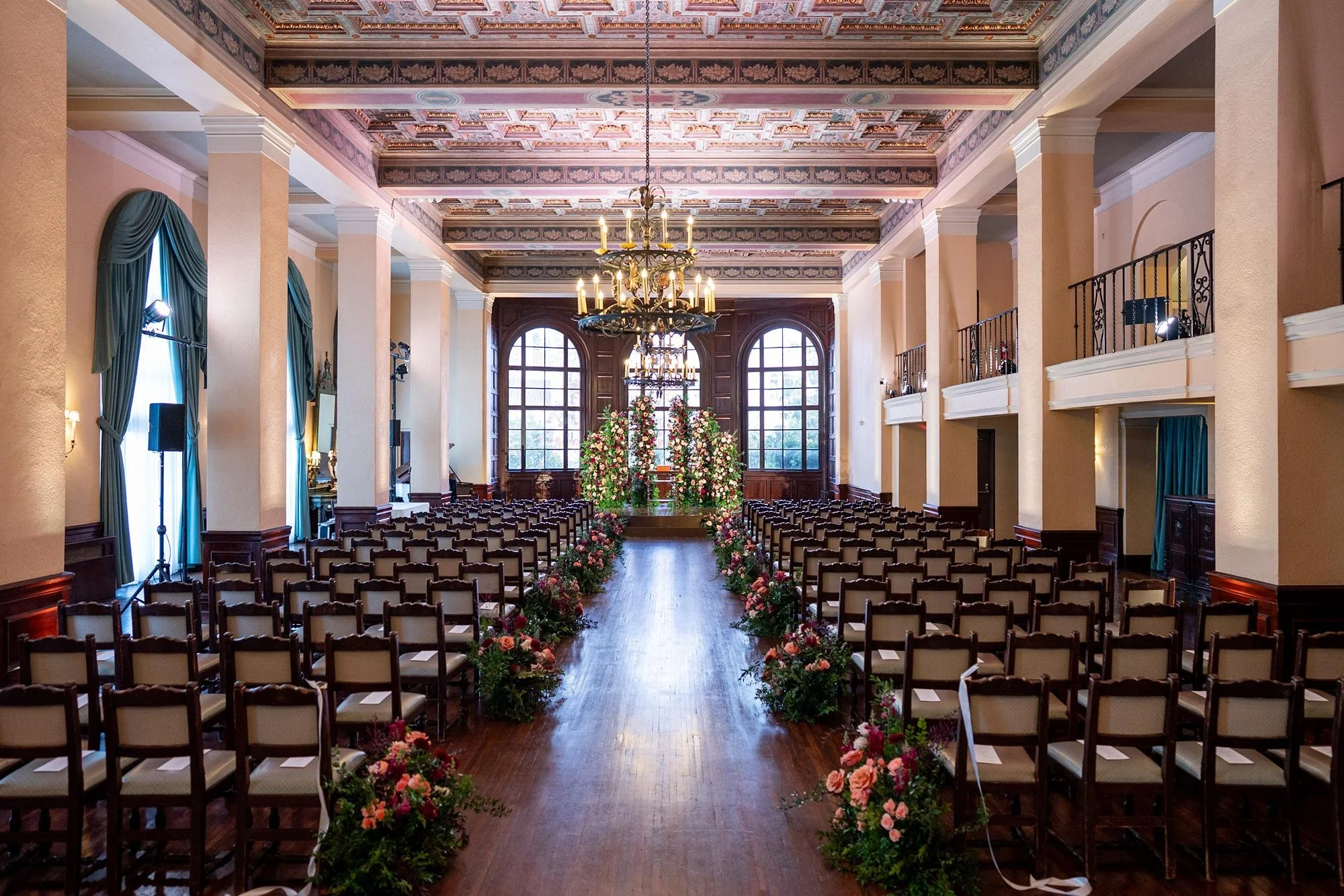 Wedding ceremony in Lounge with rose aisle runner and floral altar beneath lit ceiling at Ebell of Los Angeles