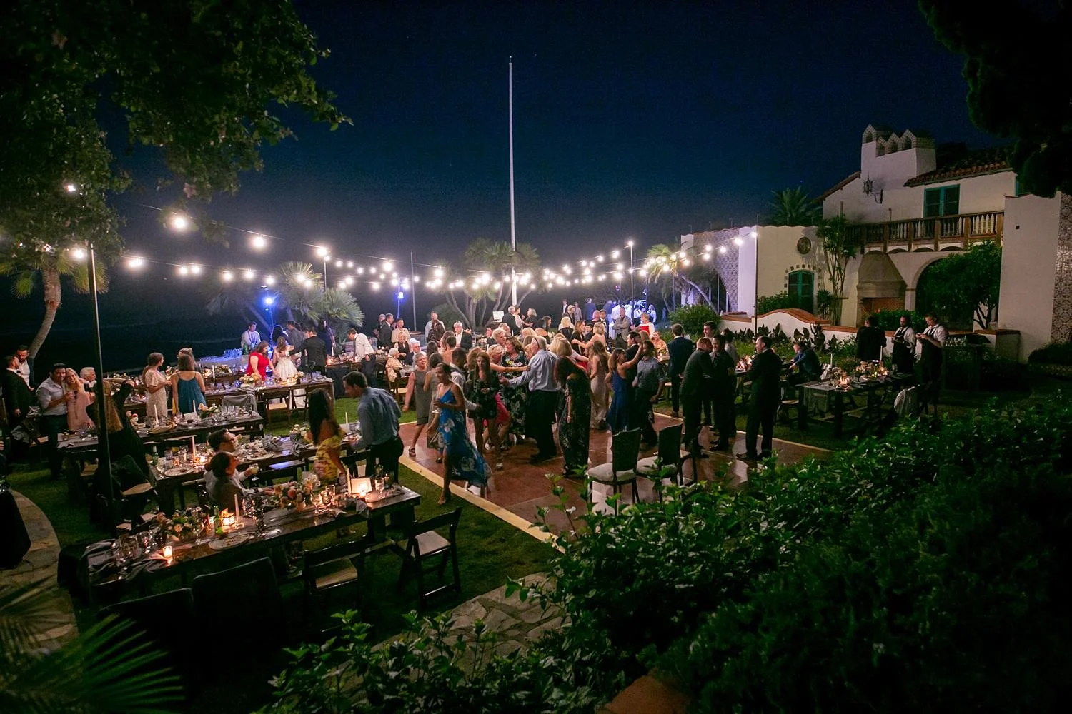 Wedding reception at Adamson House with guests dancing beneath glowing string lights