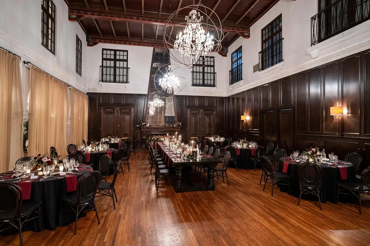 Wedding reception in the Grand Hall with black linens, candles and red florals at the Ebell of Long Beach