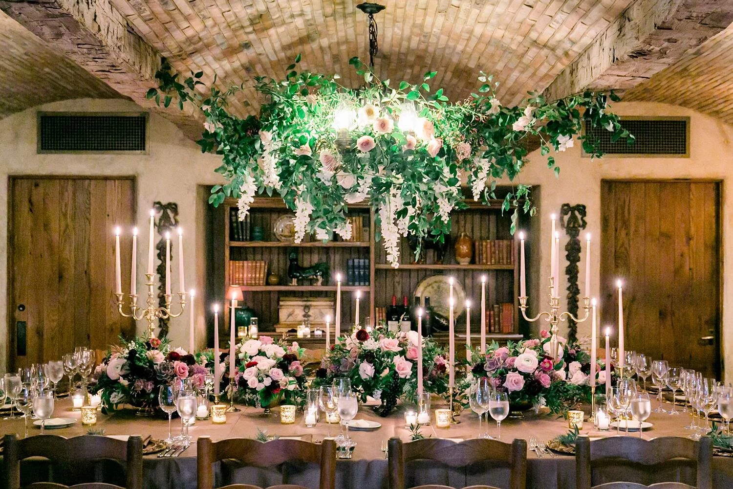 Wine Cellar dinner table with florals, taper candles, and floral chandelier during wedding at San Ysidro Ranch