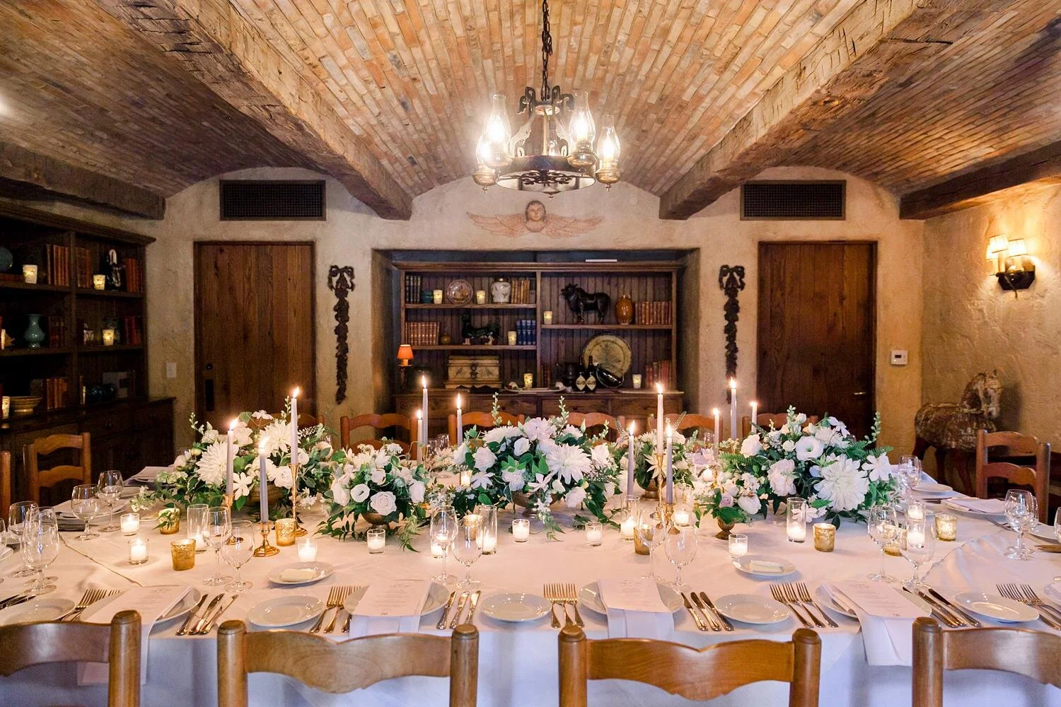 Dinner table decorated with white florals and candles for Wine Cellar wedding at San Ysidro Ranch
