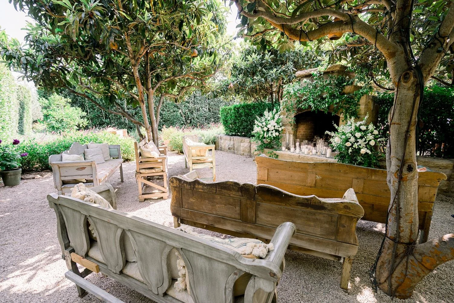 Wine Cellar Patio wedding ceremony with wooden pews, florals, and  candles in front of fireplace at San Ysidro Ranch