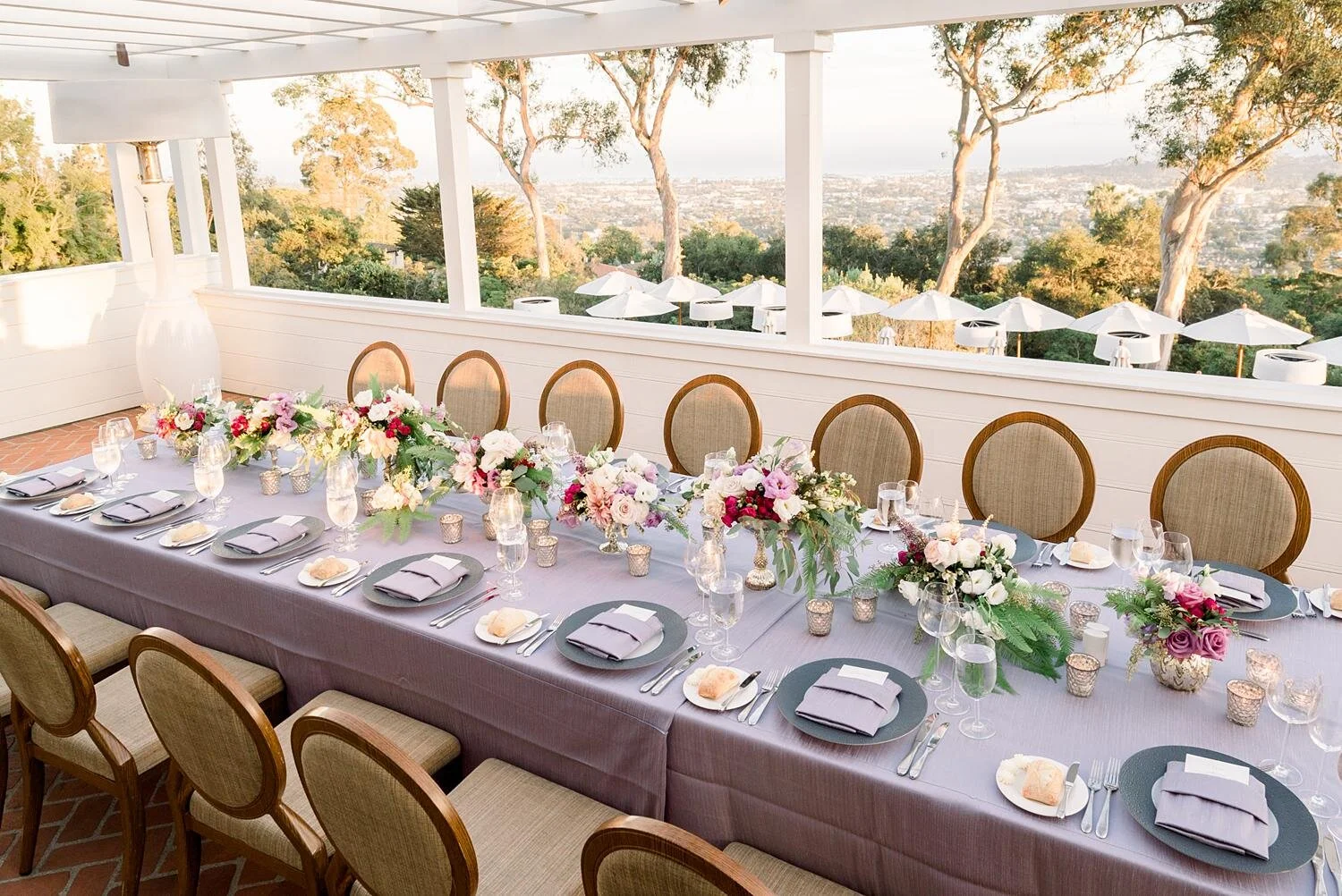 Floral centerpieces and candles for wedding reception on Fireside Patio with Santa Barbara coastline view at Belmond El Encanto