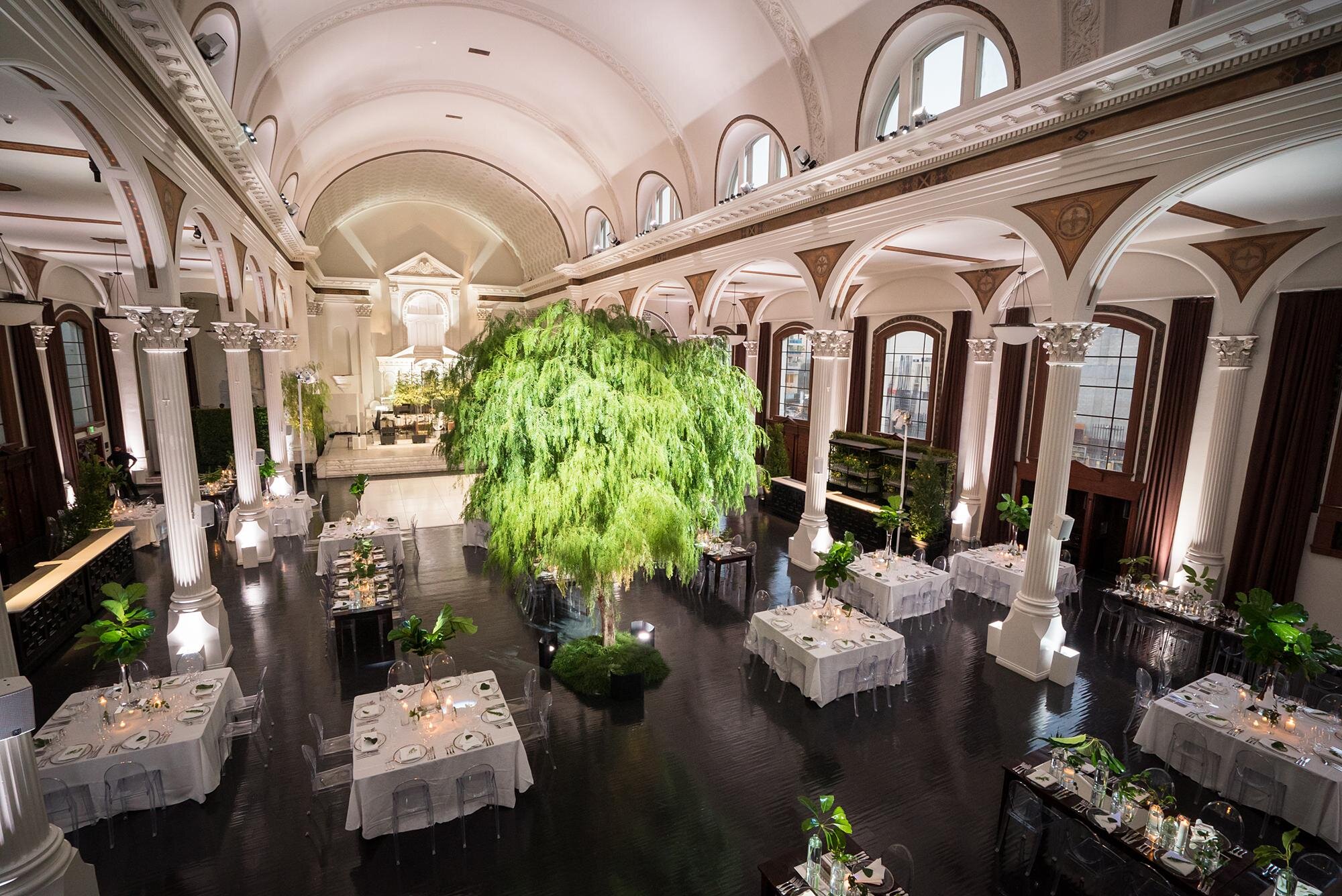 Wide view of a cathedral wedding reception with tables and lighting at Vibiana in Los Angeles