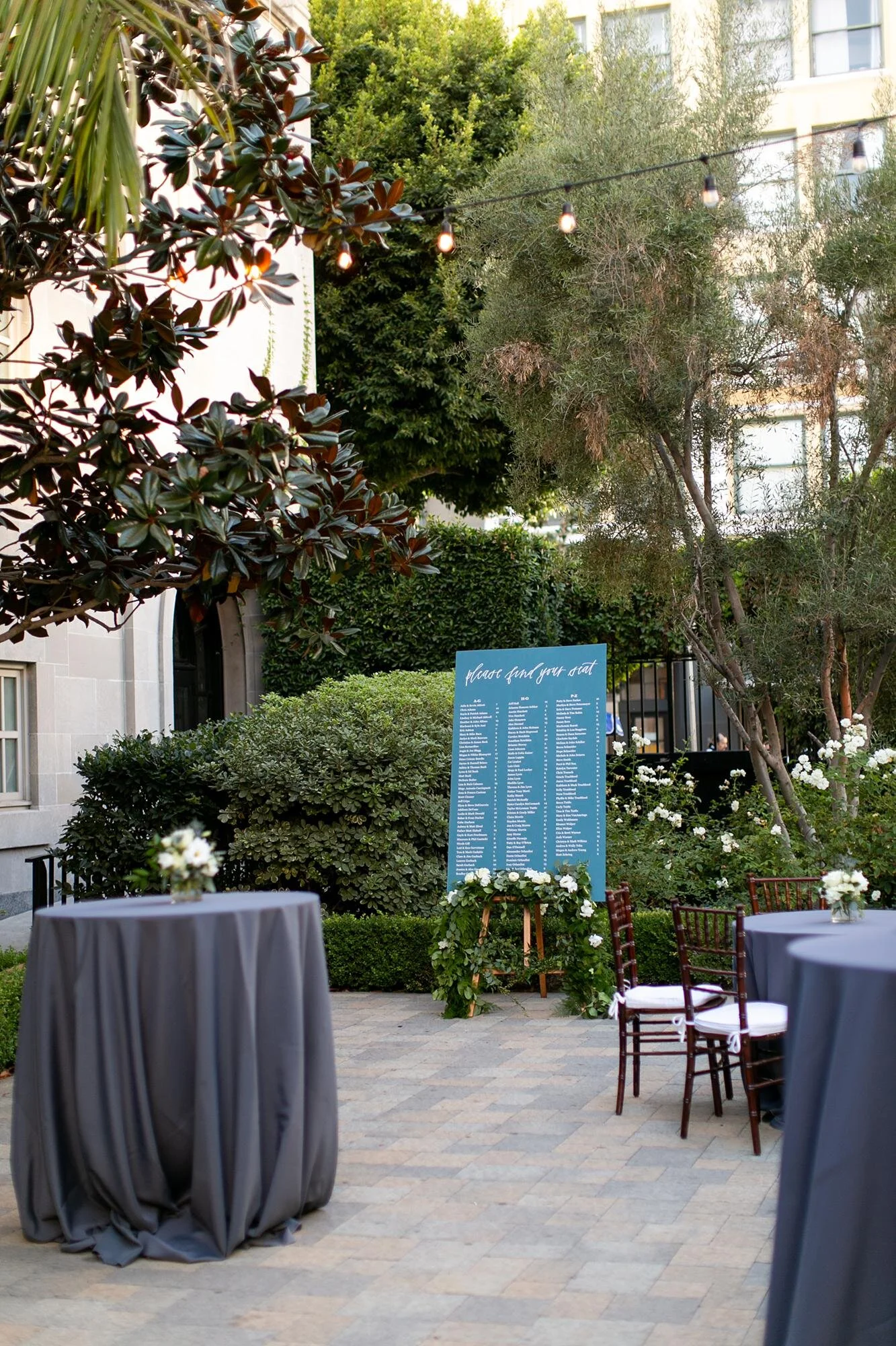Cocktail tables with blue linens and seating chart during a wedding cocktail hour at Vibiana in Los Angeles