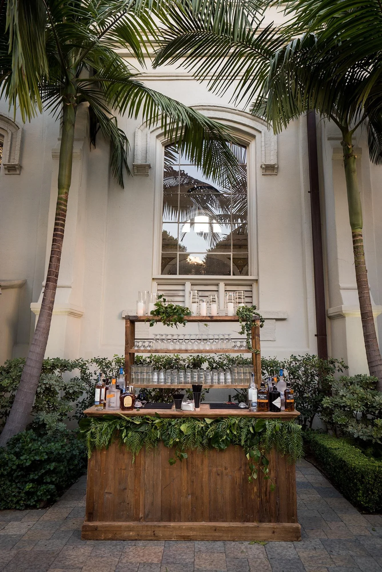 Wooden cocktail bar framed by palms and cathedral windows at a Vibiana wedding in Los Angeles