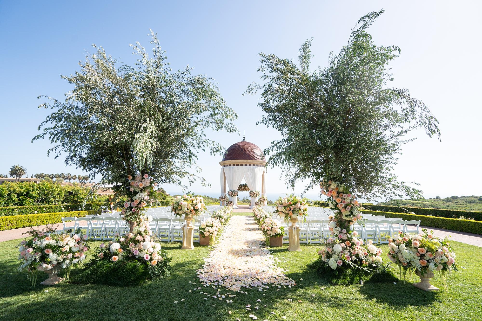 Wedding ceremony on the Event Lawn with olive trees and pastel florals at Pelican Hill
