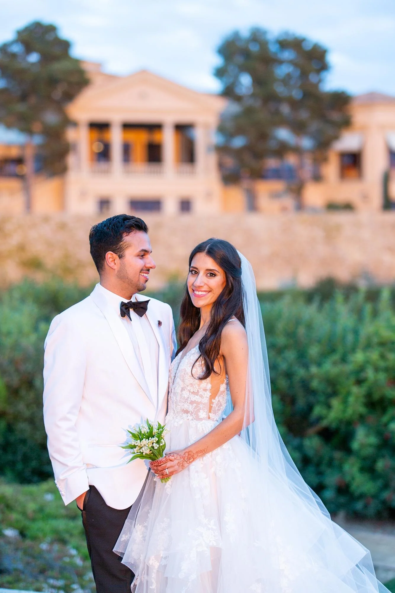 Wedding portraits of bride and groom at sunset with resort in background at Pelican Hill