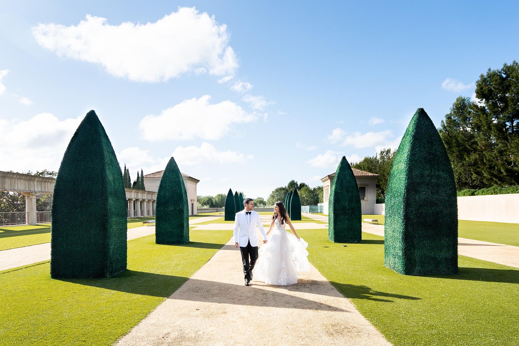 Bride and groom walking together in manicured rooftop garden wedding portraits at Pelican Hill