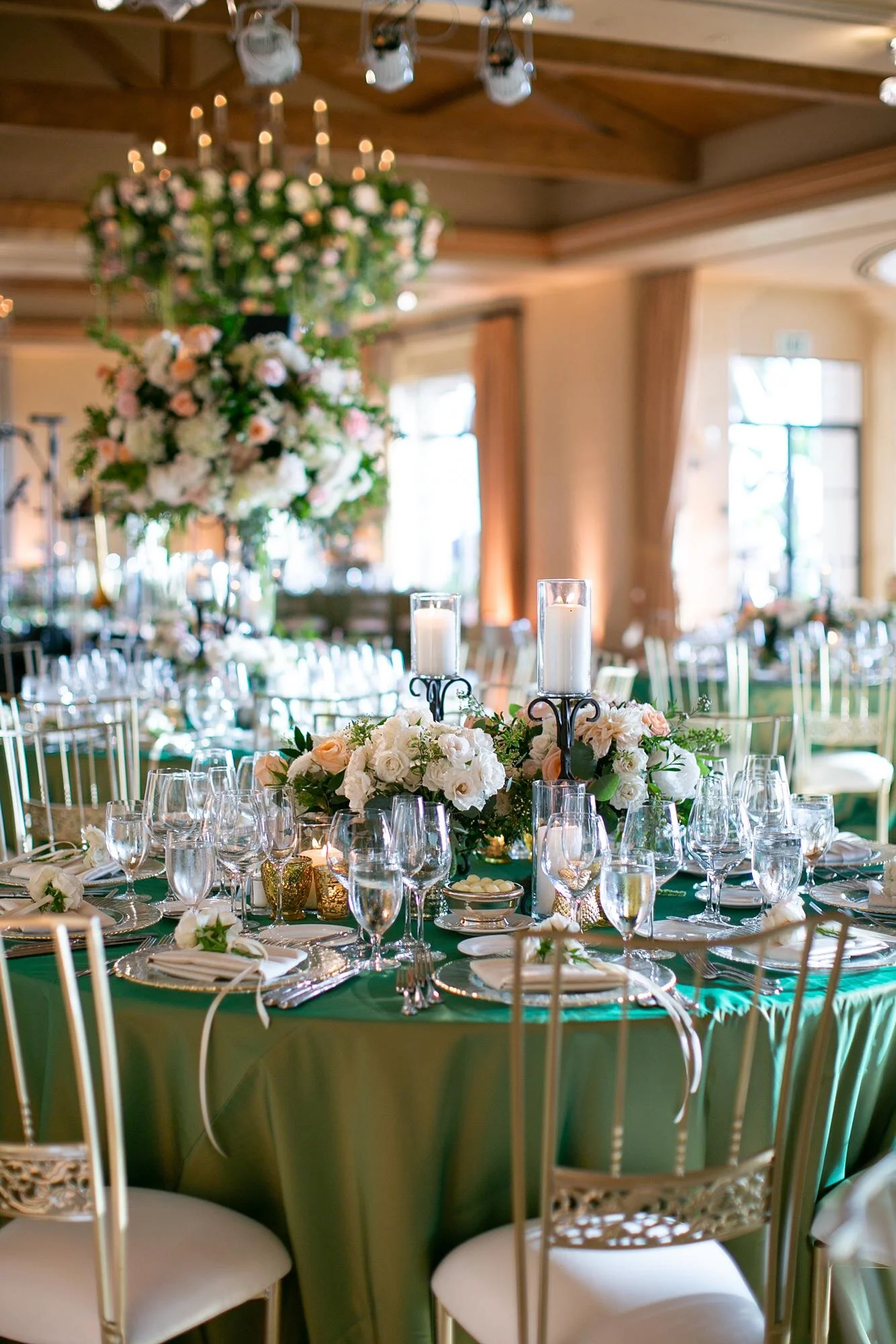 Circular tables with floral centerpieces and chandelier-draped florals during Pelican Hill wedding reception 9.