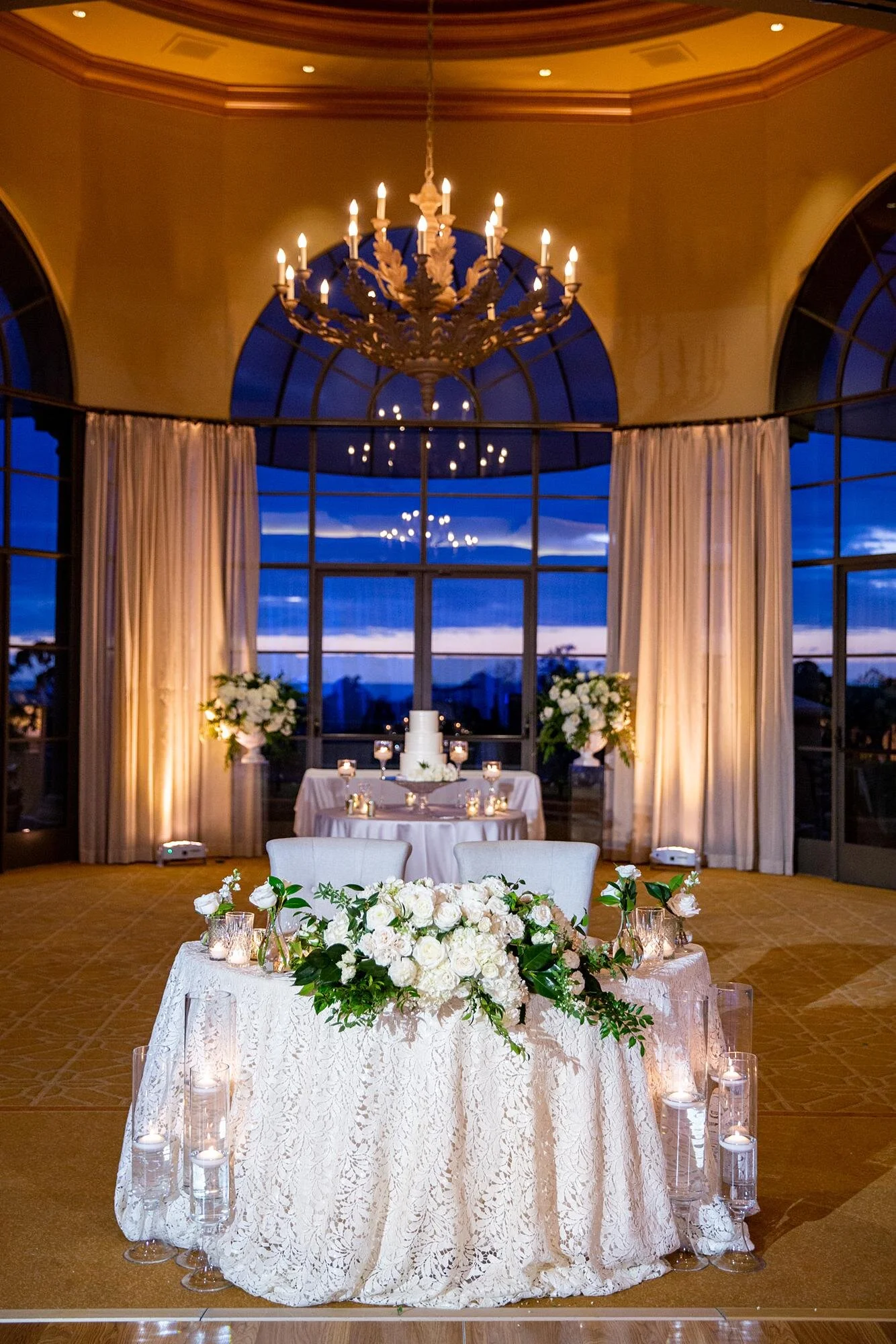 Sweetheart table against arched window at sunset during Pelican Hill wedding reception
