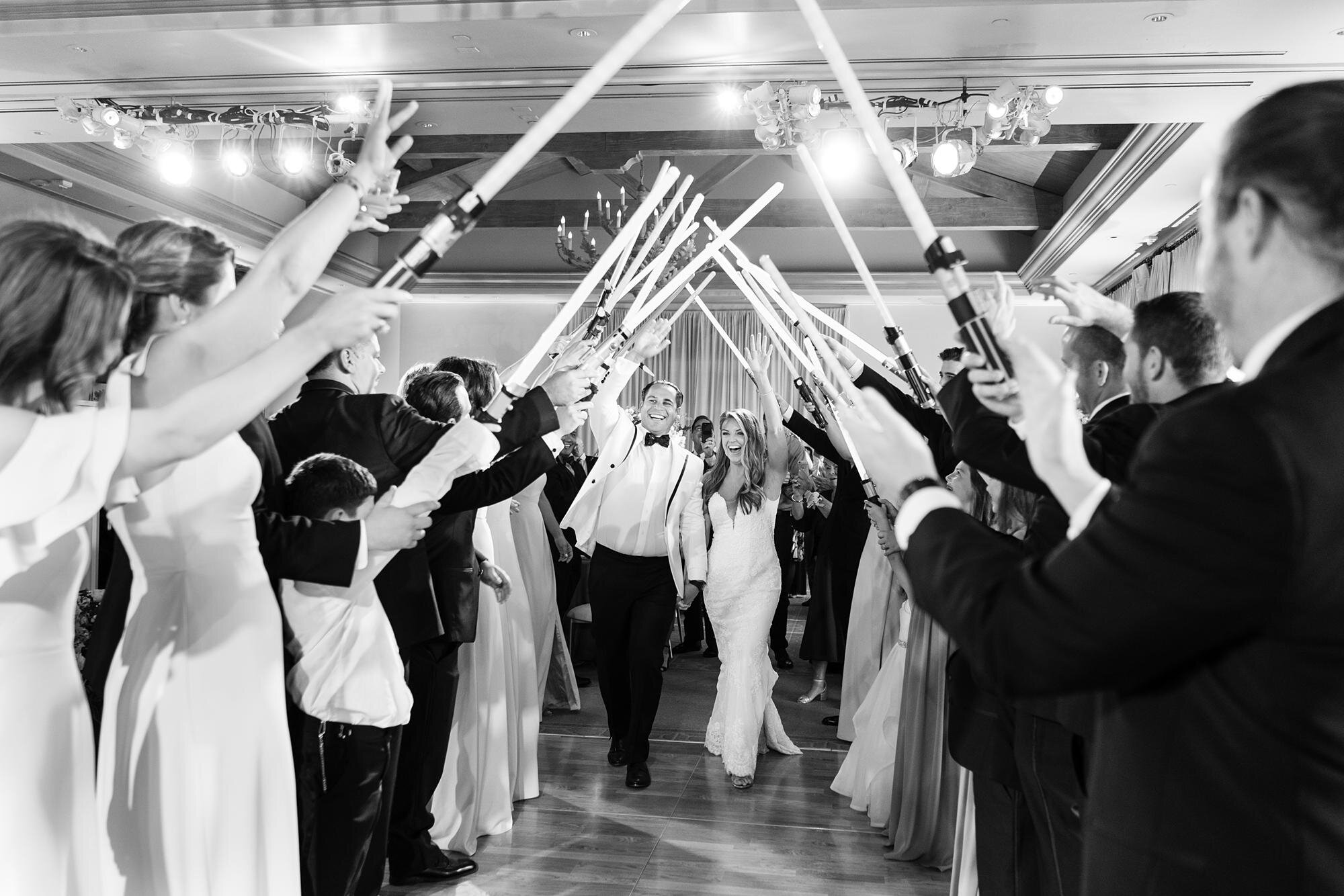 Bride and groom entering between guests waving light sabers at Pelican Hill wedding reception