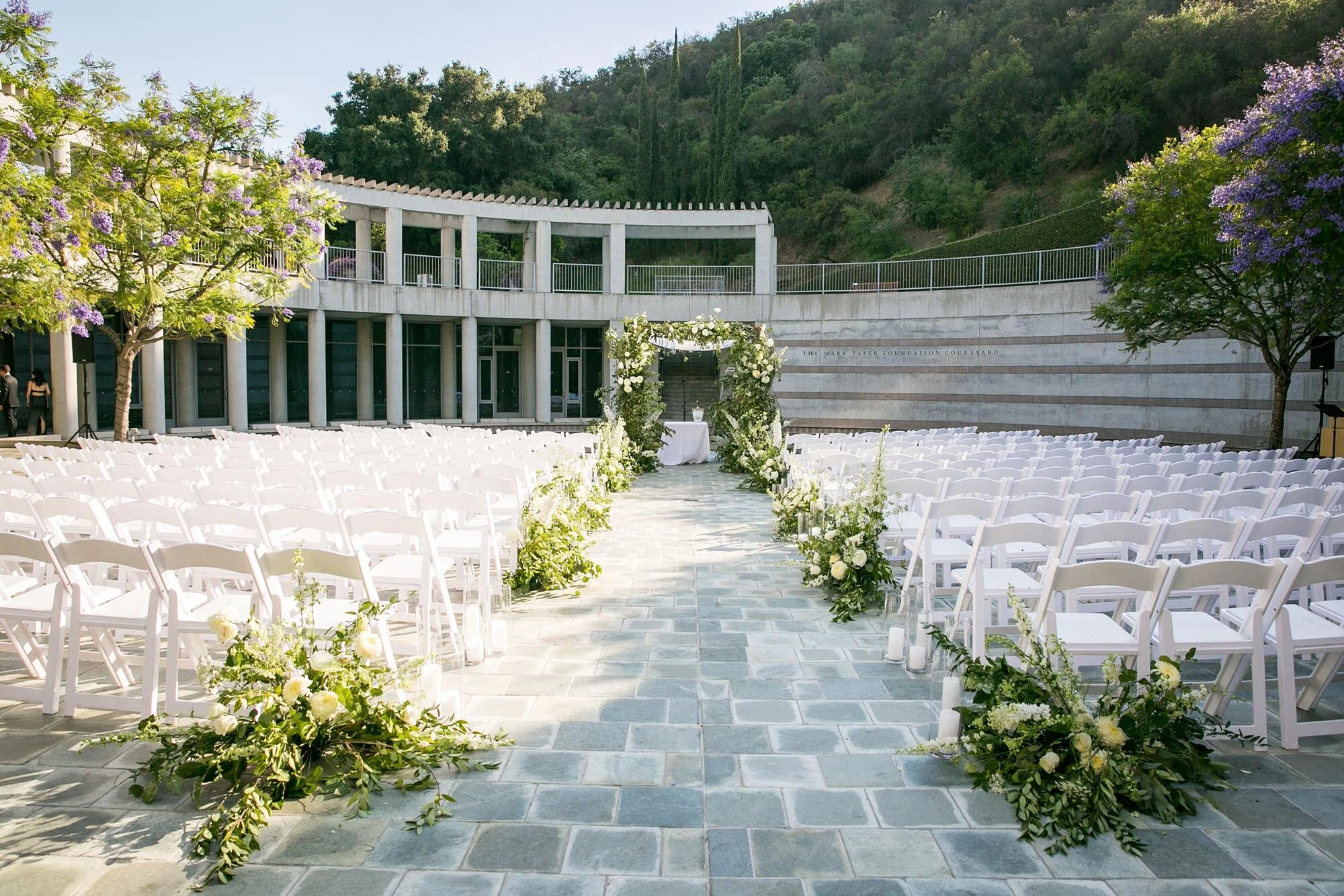 Wide view of a wedding ceremony in the Taper Courtyard during the afternoon at the Skirball Cultural Center