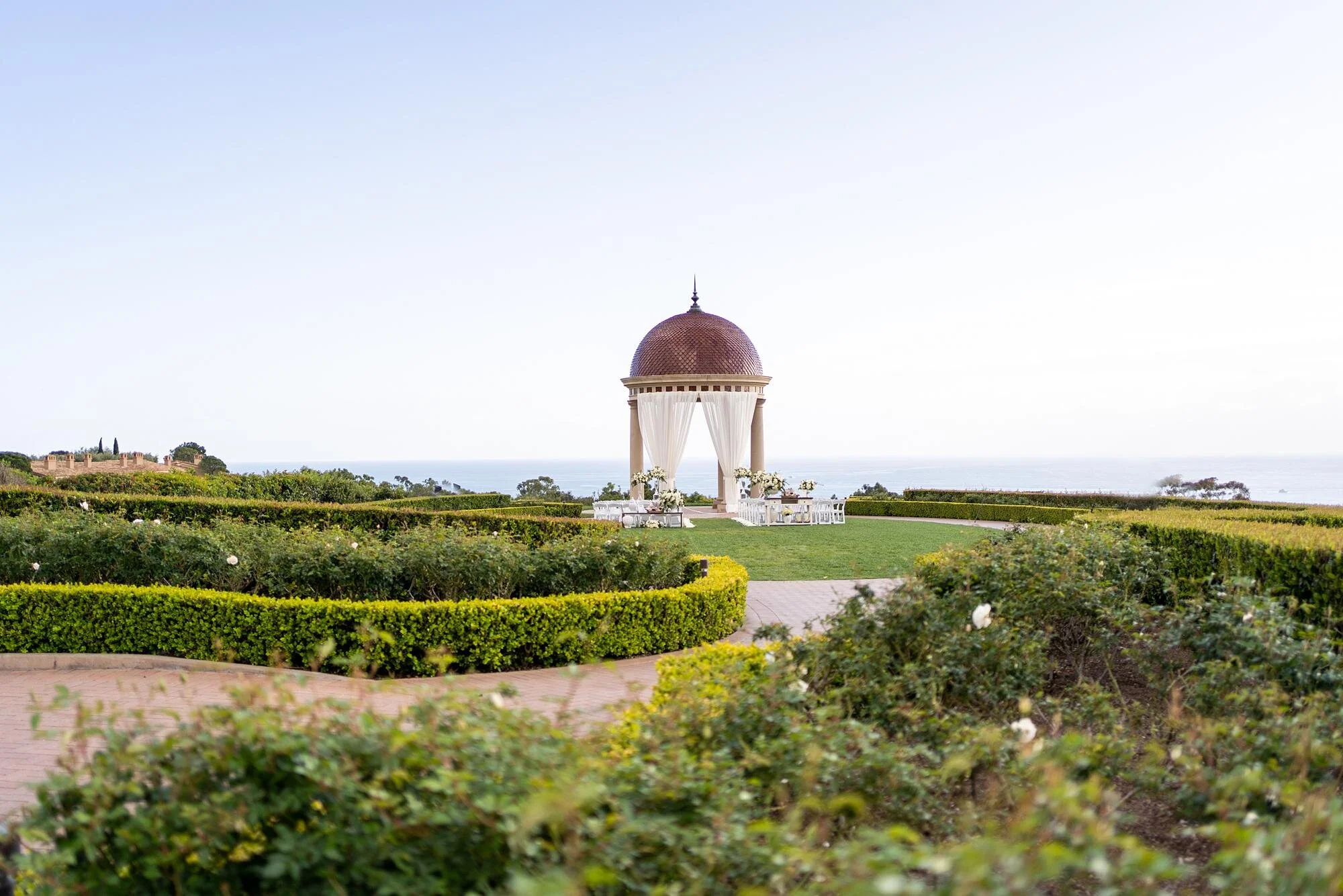 Wedding ceremony on the Event Lawn with winding path and ocean view at Pelican Hill