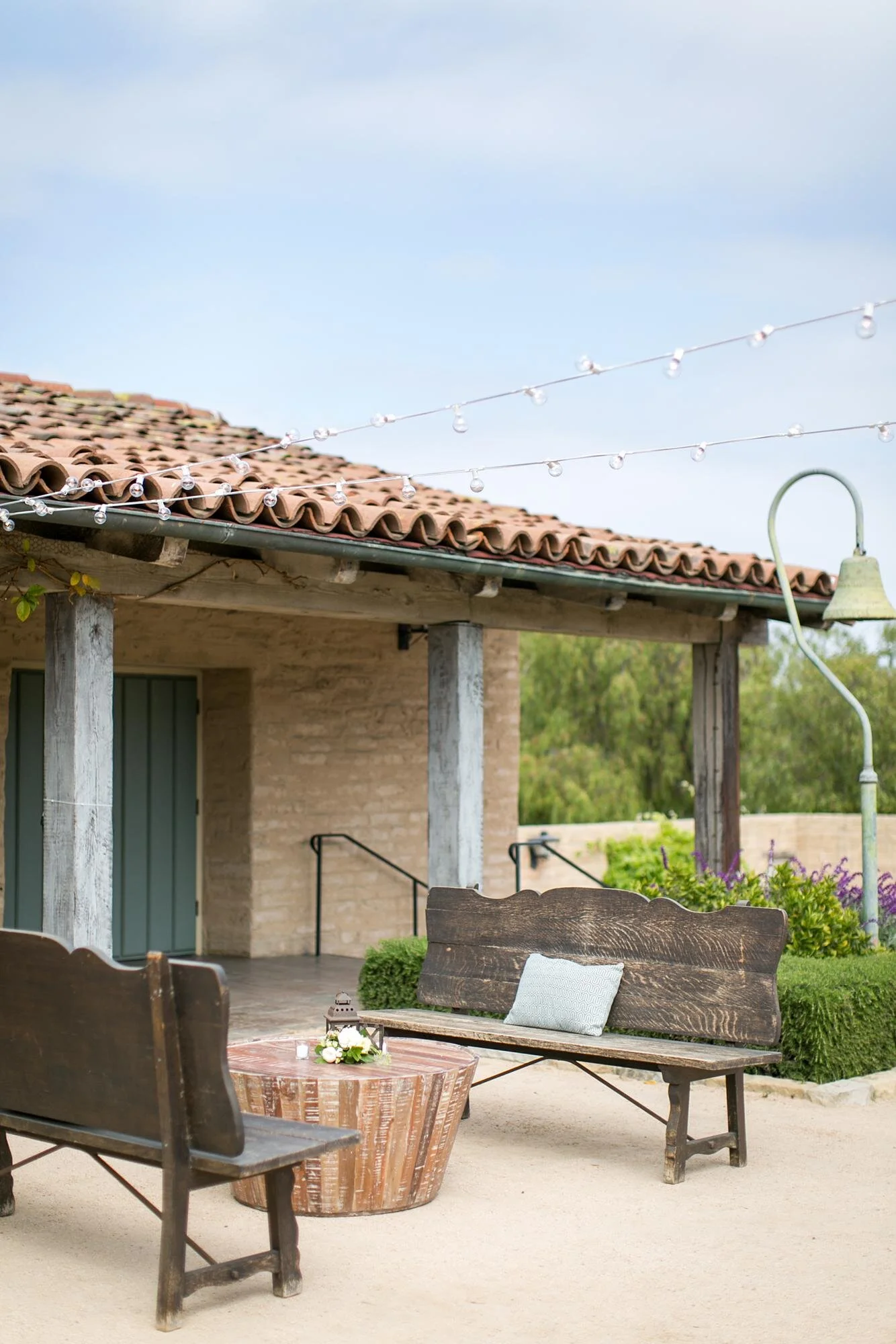 Wedding cocktail hour seating area with wooden benches in the Santa Barbara Historical Museum Courtyard