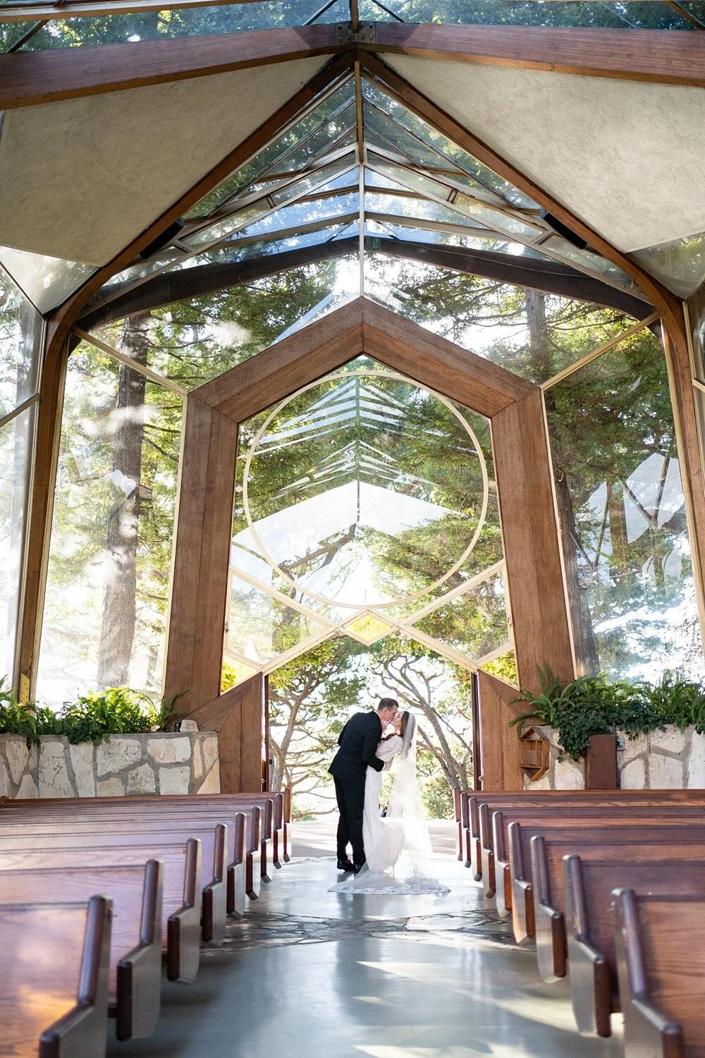 Wedding portraits of bride and groom kissing in the glass doorway at Wayfarers Chapel