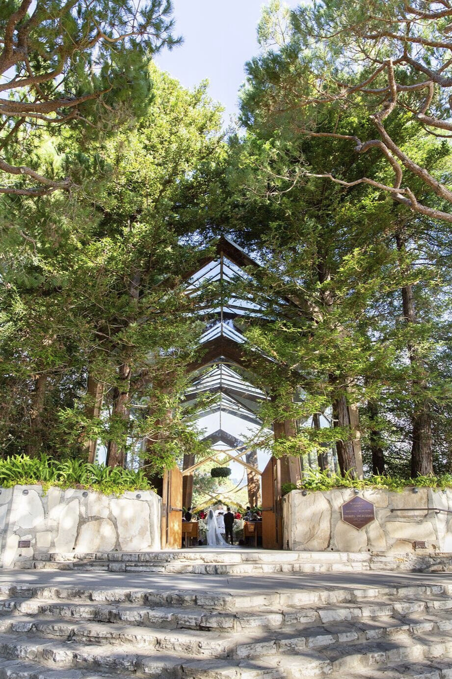 Wedding ceremony visible through glass walls from outside Wayfarers Chapel