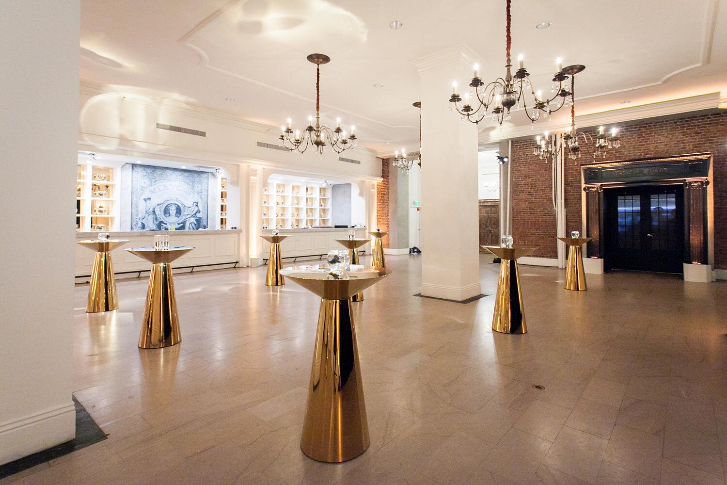 Wedding cocktail hour with modern gold tables arranged in Palm Court at the Alexandria Ballrooms