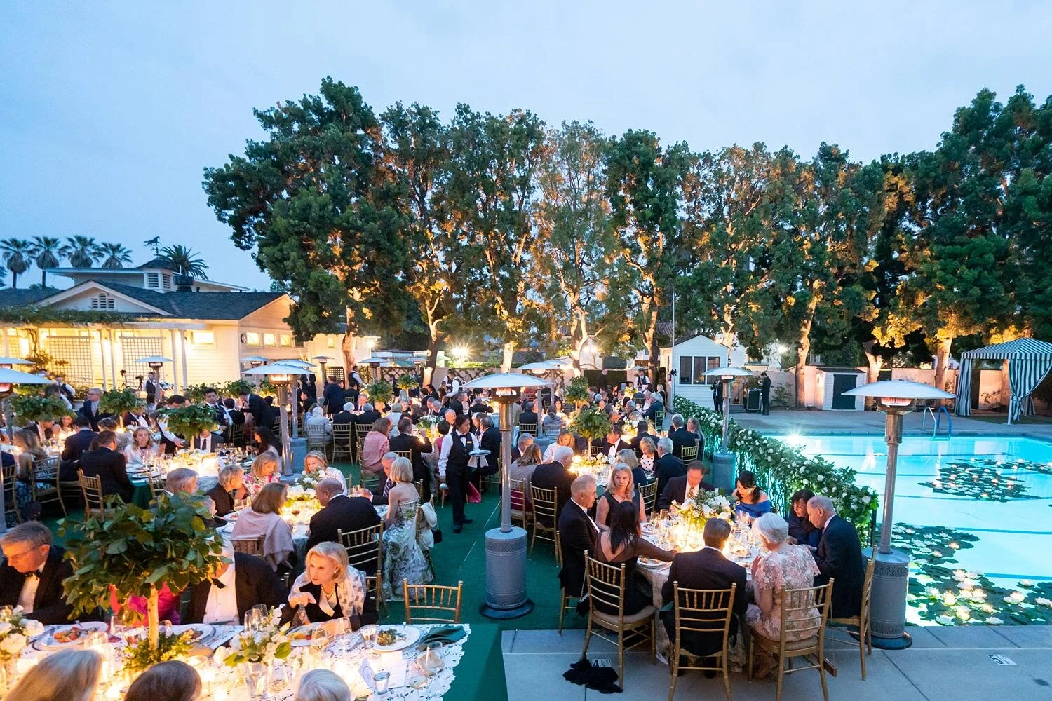 Wedding reception dinner at sunset with guests seated on the Back Lawn at the Valley Hunt Club