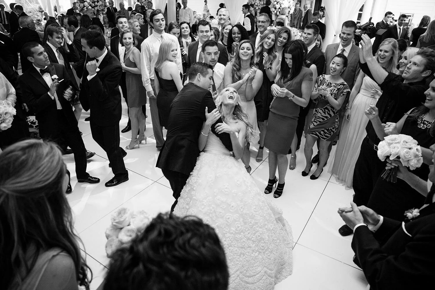 Wedding reception dancing at Annandale Golf Club as groom dips bride on the dance floor surrounded by guests