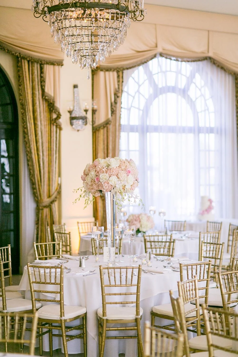 Wedding reception at Riviera Country Club with a tall floral centerpiece near an arched window