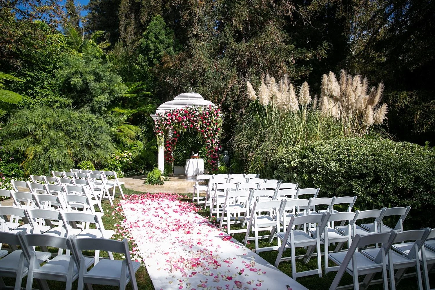 Wedding ceremony gazebo decorated with cascading pink florals beside Swan Lake at Hotel Bel Air