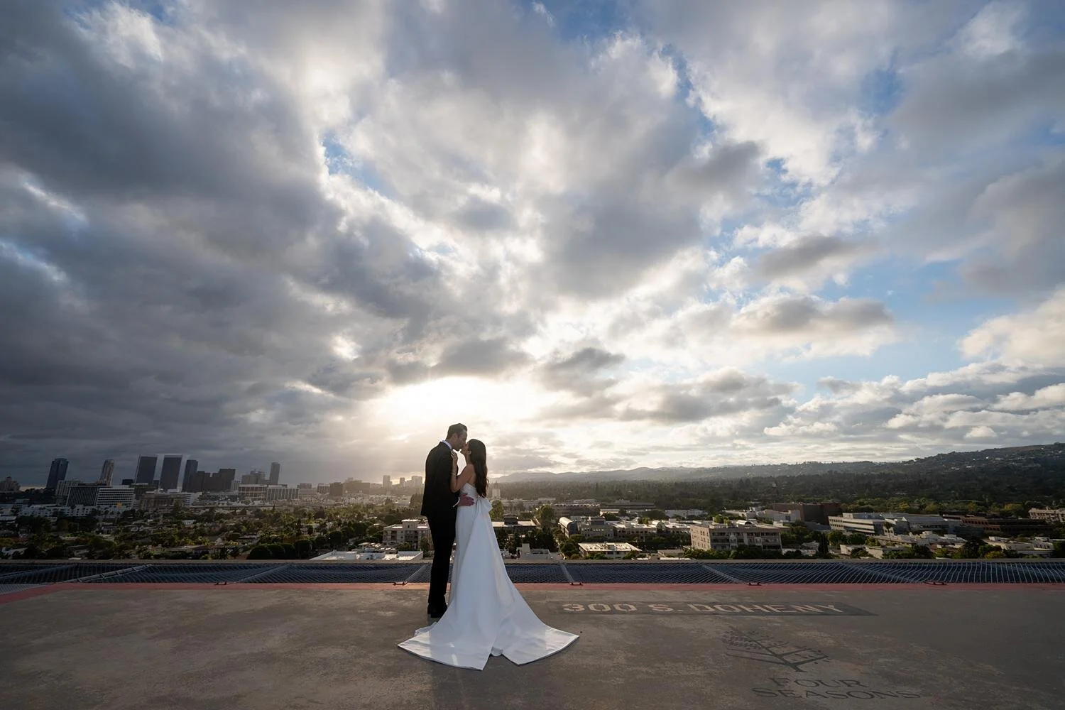 Bride and groom posing for wedding portraits on a rooftop at sunset at the Four Seasons Los Angeles