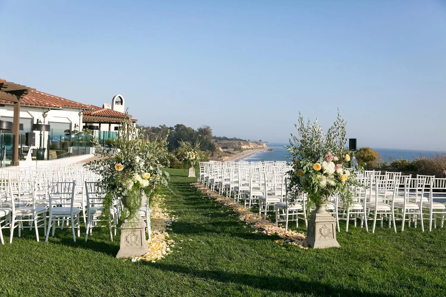 Wedding ceremony entrance with large floral arrangements on the Bluff Lawn at Ritz Carlton Bacara