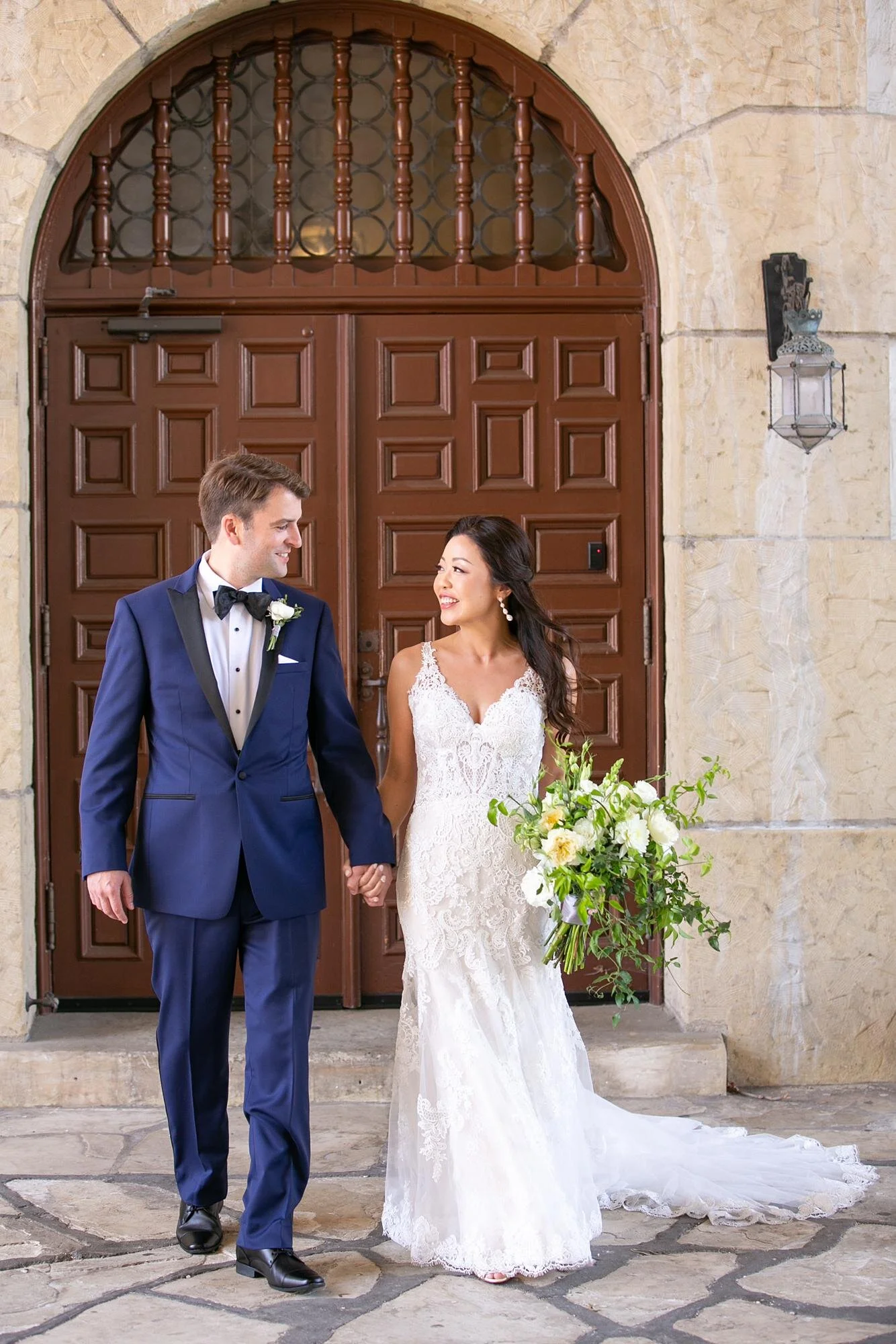 Wedding portrait of a couple walking in front of carved wooden doors at the Santa Barbara Courthouse