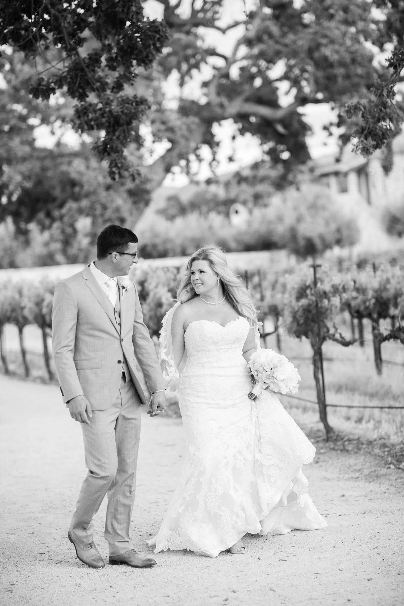 Wedding portraits at Sunstone Winery and Villa of a couple walking through the vineyard