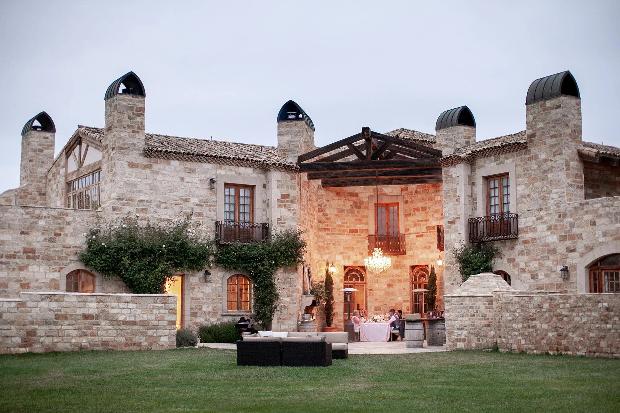Wedding reception at Sunstone Winery and Villa with guests dining outdoors at night under chandeliers