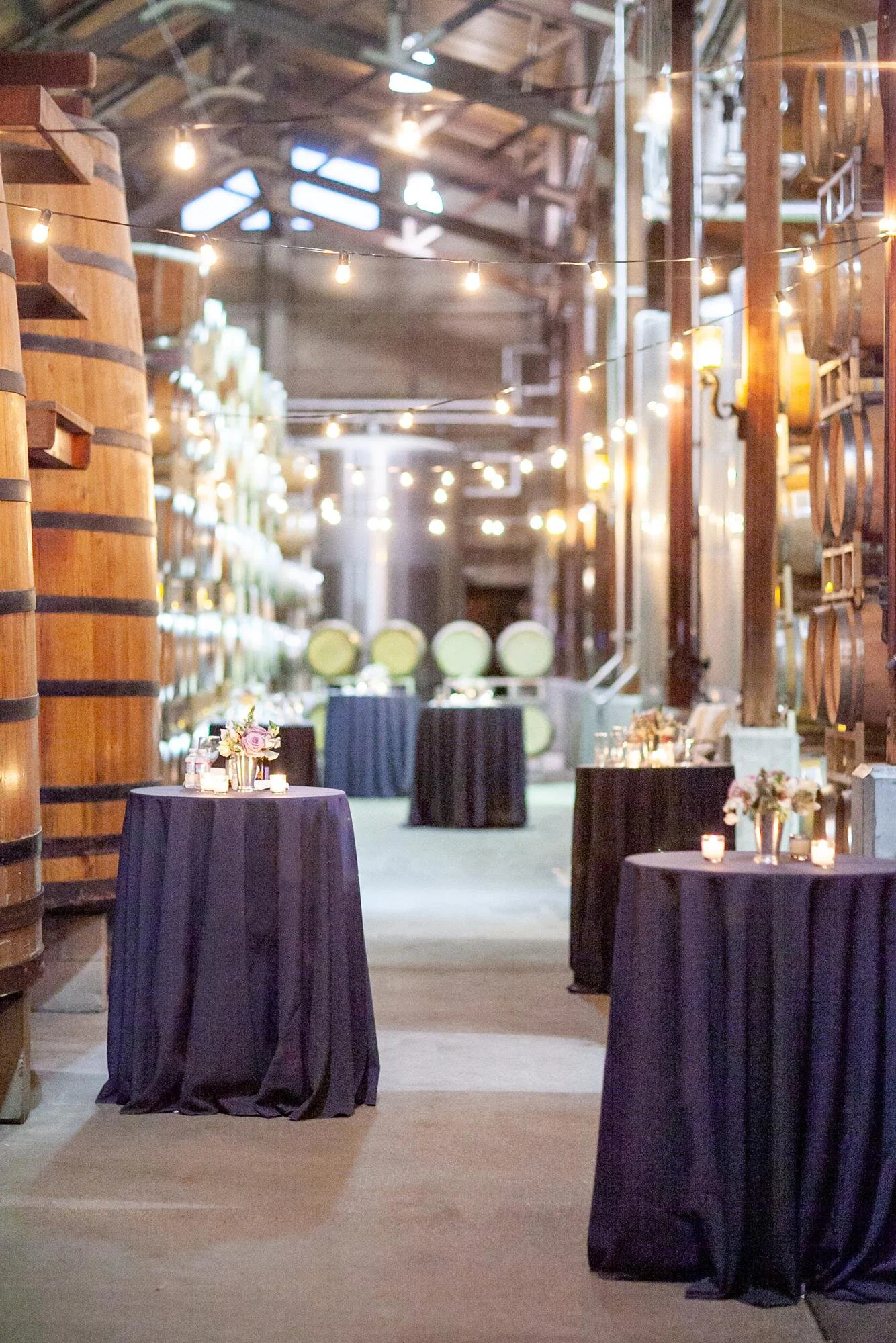 Wedding cocktails at Firestone Winery in the Barrel Room with string lights and cocktail tables