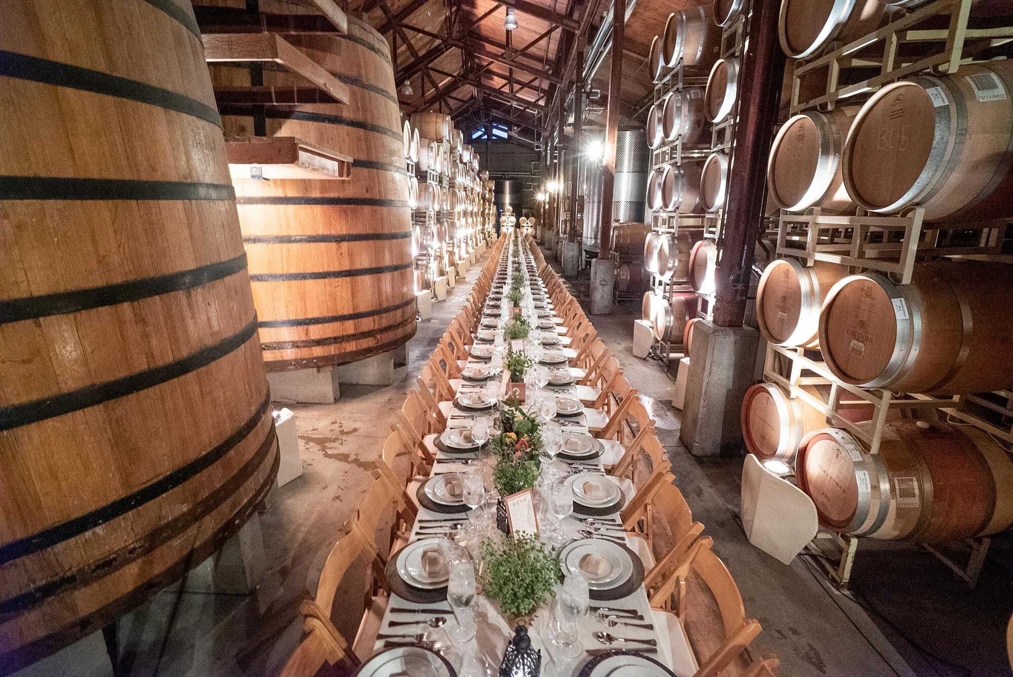 Wedding reception at Firestone Winery with a long dinner table set inside the Barrel Room