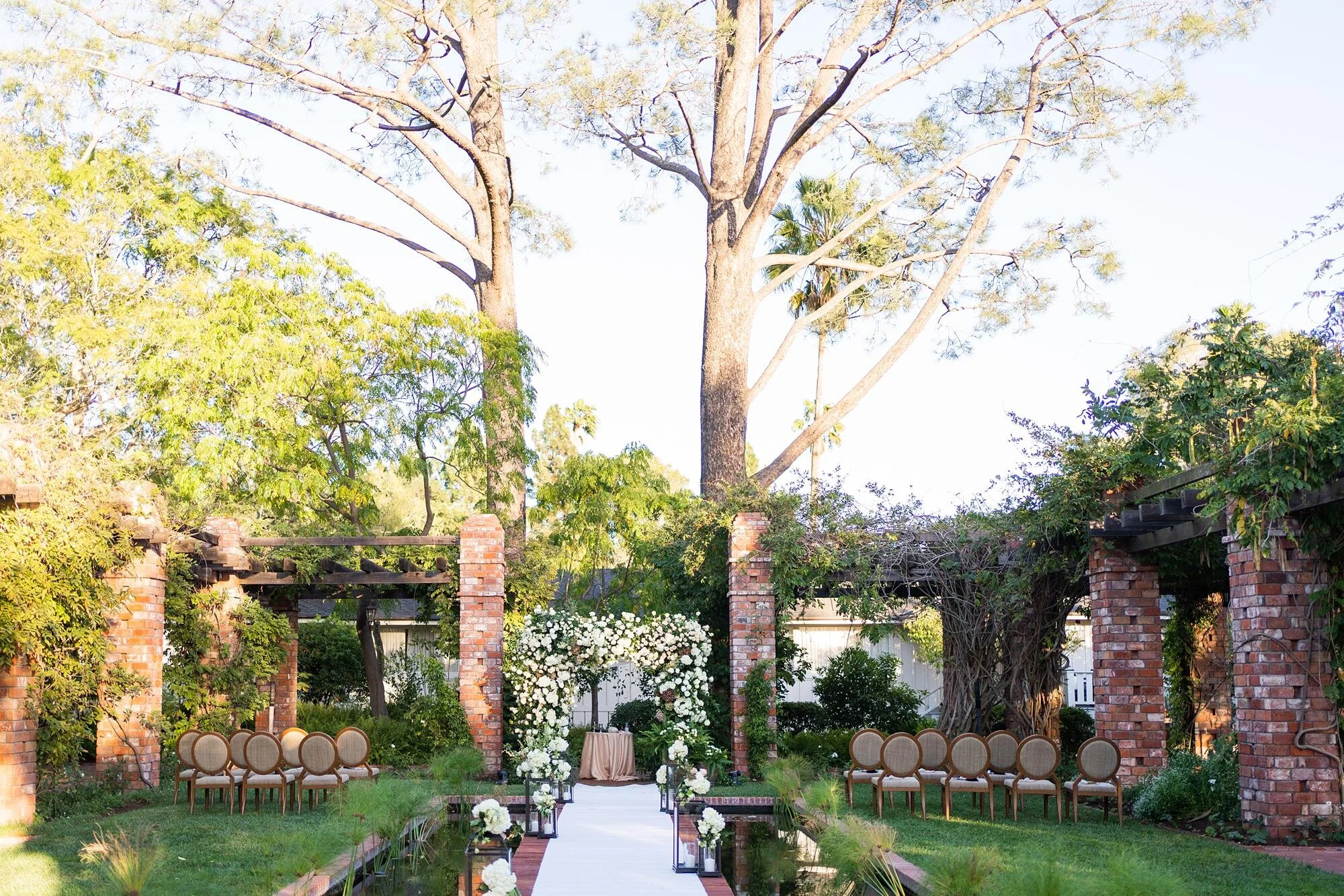 Intimate Jewish wedding ceremony under rose-covered chuppah at Arbor and Lilly Pond, Belmond El Encanto