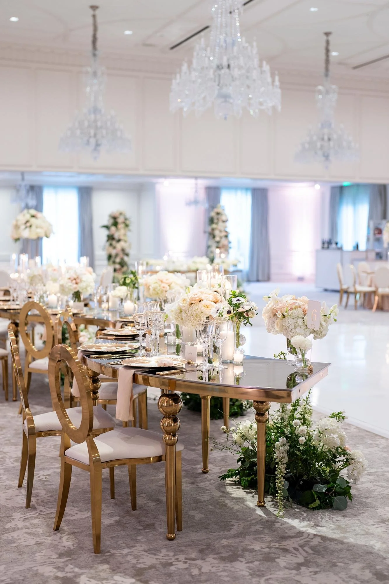 Detailed view of a mirrored serpentine table with florals for a Chandelier Ballroom wedding reception at Rosewood Miramar Beach