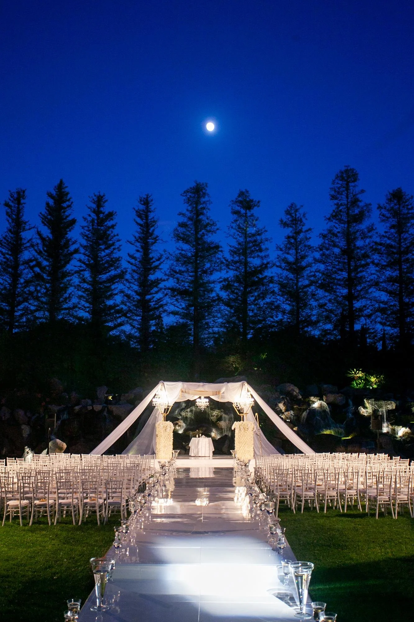 Wedding ceremony at Four Seasons Westlake at night on the Waterfall Lawn with a glowing white walkway