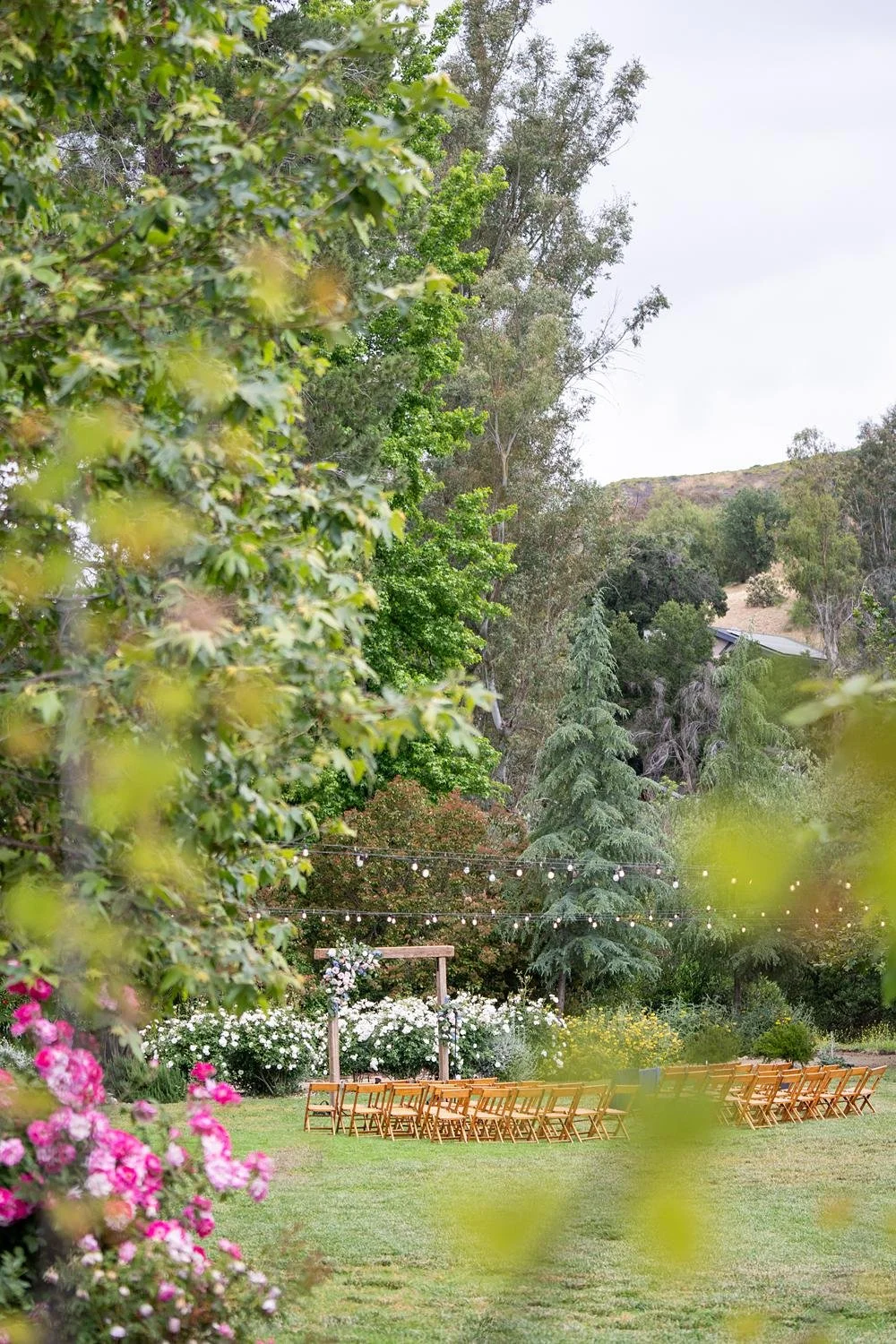 Wedding ceremony on the lawn at the Lodge at Malibou Lake featuring an arch decorated with cascading roses