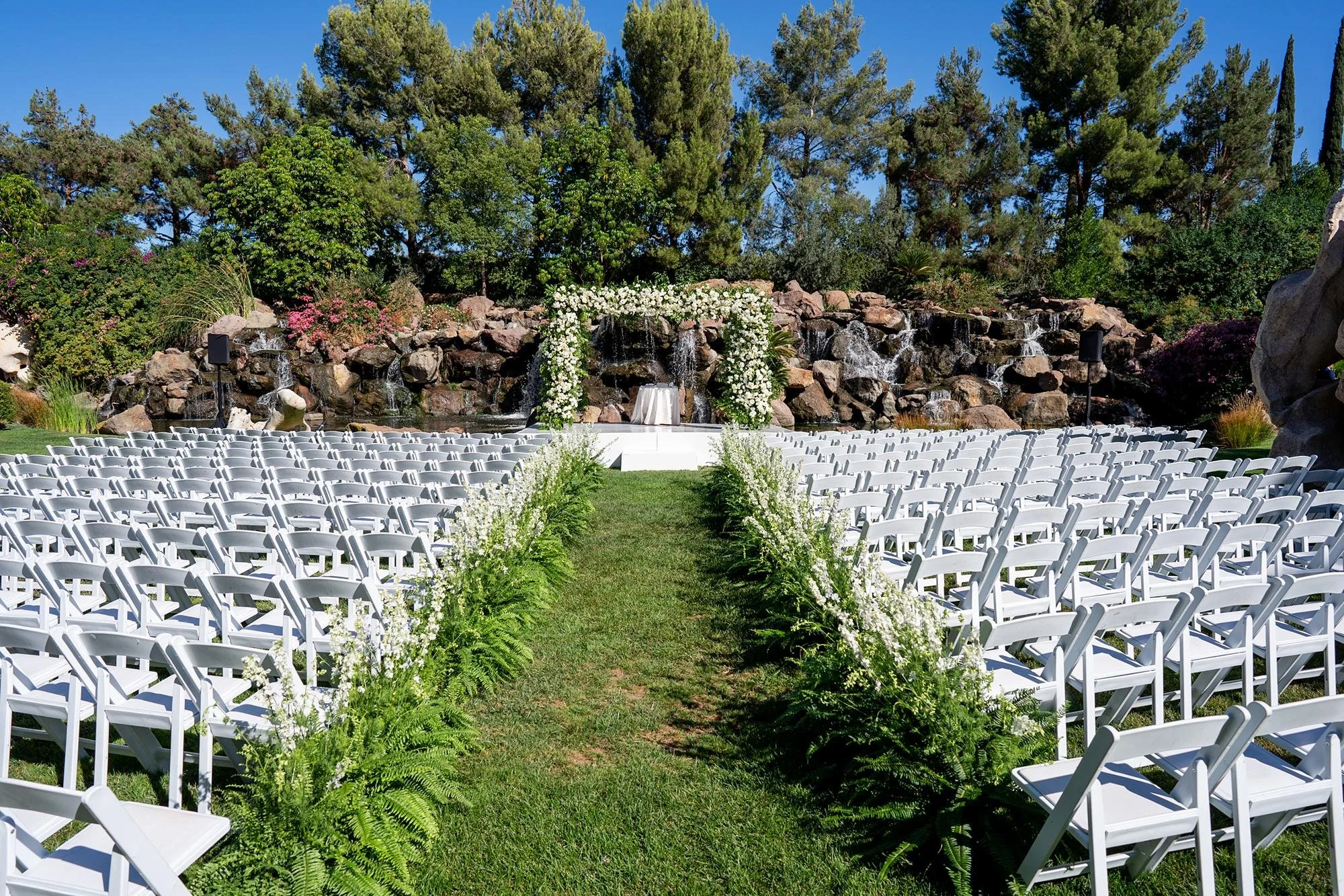 Wedding ceremony at Four Seasons Westlake on the Waterfall Lawn with a fern-lined aisle