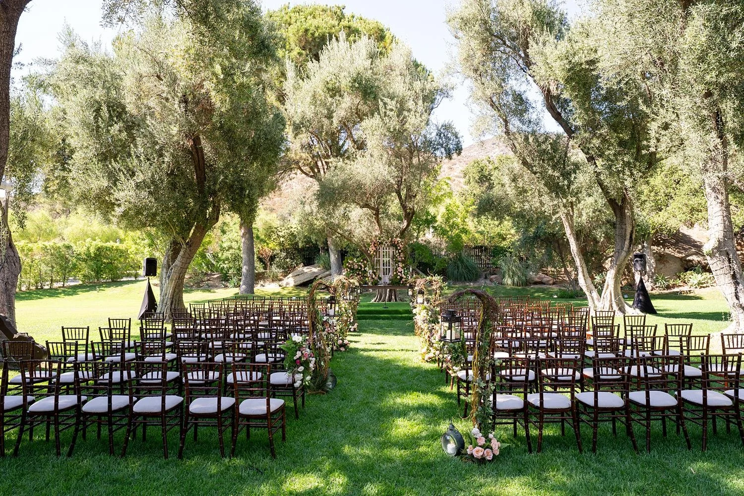 Wide view of a Sitting Bull wedding ceremony set under oak trees at Hummingbird Nest Ranch