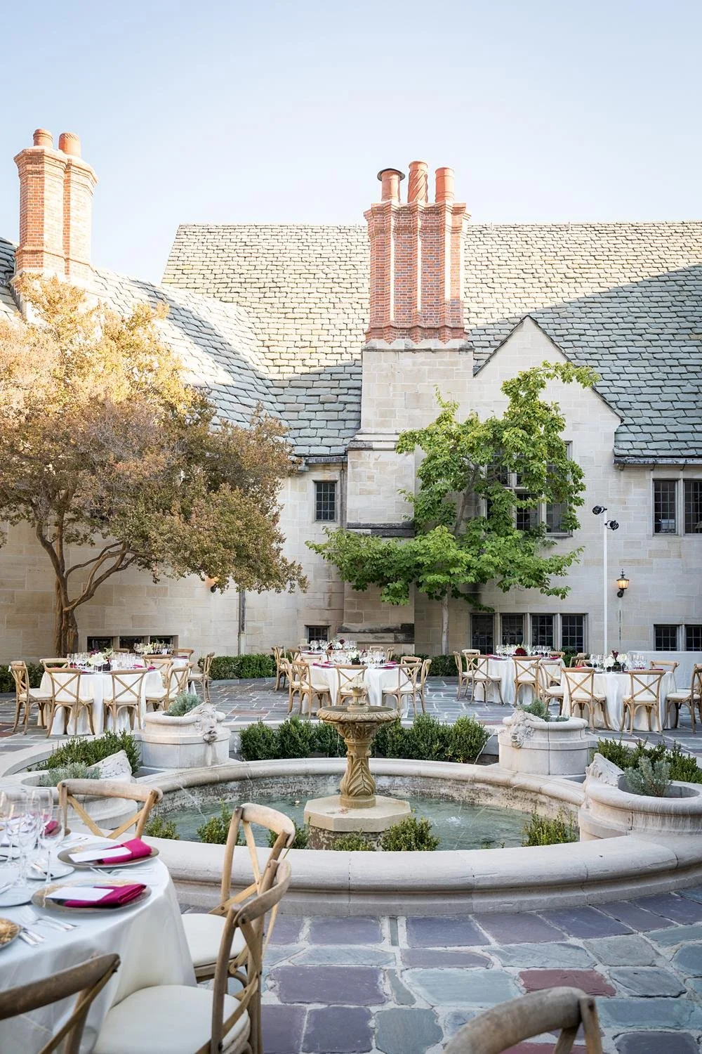 Wedding reception detail of floral centerpiece with fountain and cypress trees in the Inner Courtyard at Greystone Mansion