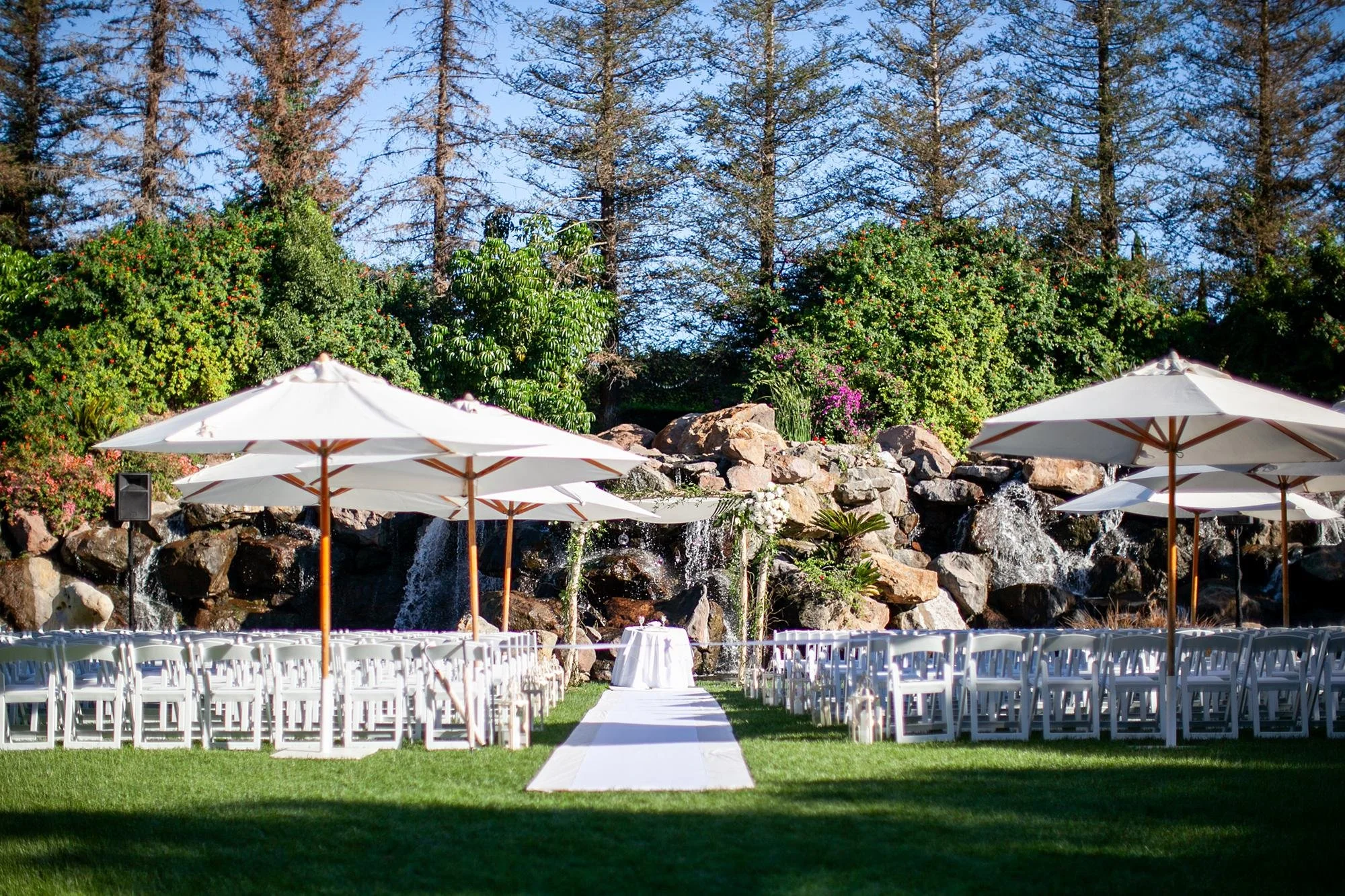 Wedding ceremony at Four Seasons Westlake featuring white umbrellas on the Waterfall Lawn