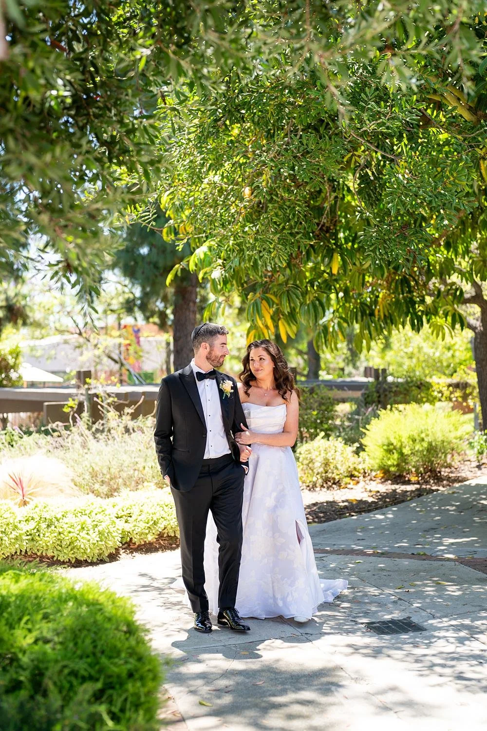 Wedding portraits of bride and groom walking among trees at Stephen Wise Temple