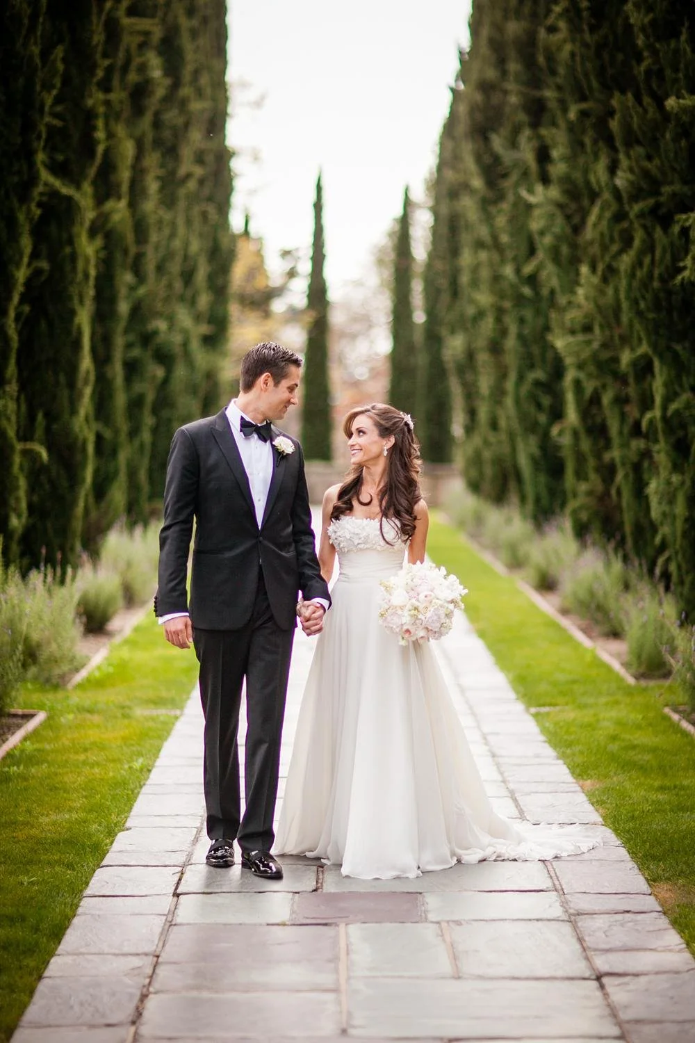 Wedding portrait of bride and groom walking together along the Cypress Walk at Greystone Mansion