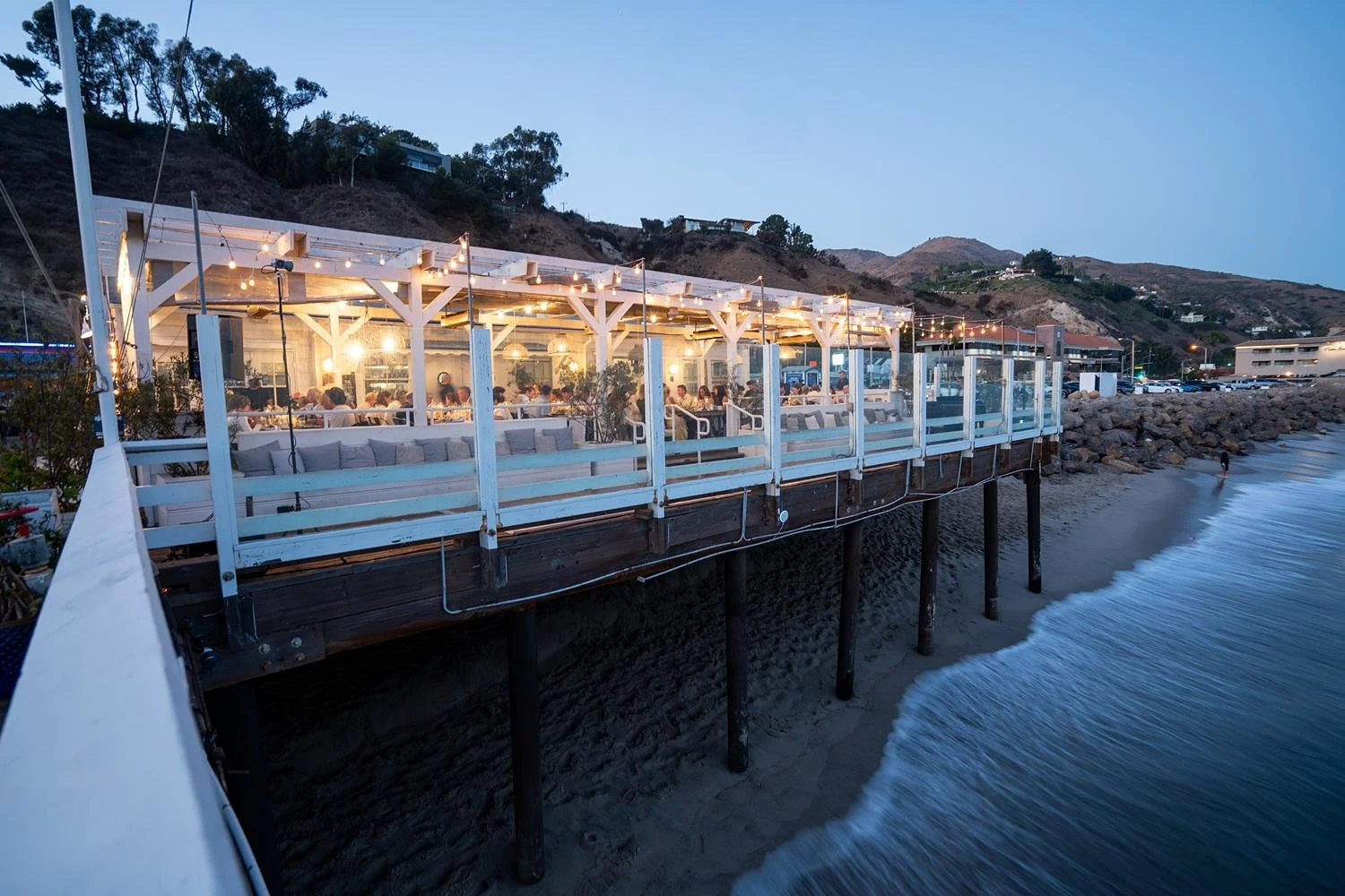 Wedding reception at Malibu Farm at the Pier at night with ocean waves hitting pier
