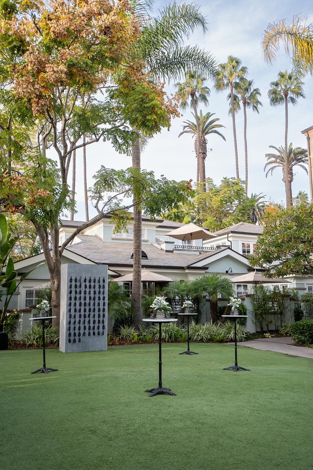 Cocktail tables with custom seating chart under tall palms during a wedding at Fairmont Miramar