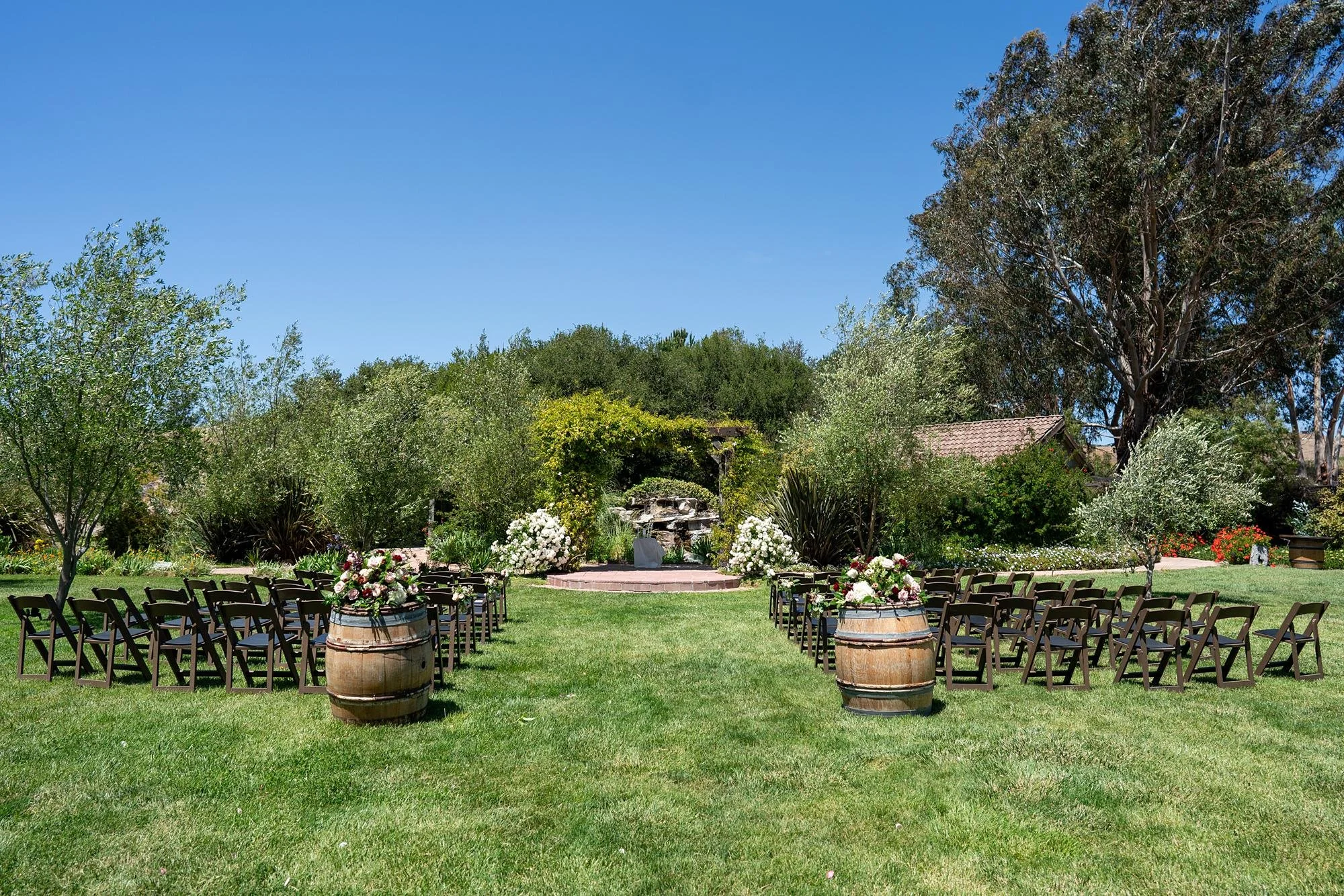 Wedding ceremony décor featuring floral arrangements on wine barrels on the lawn at La Arboleda