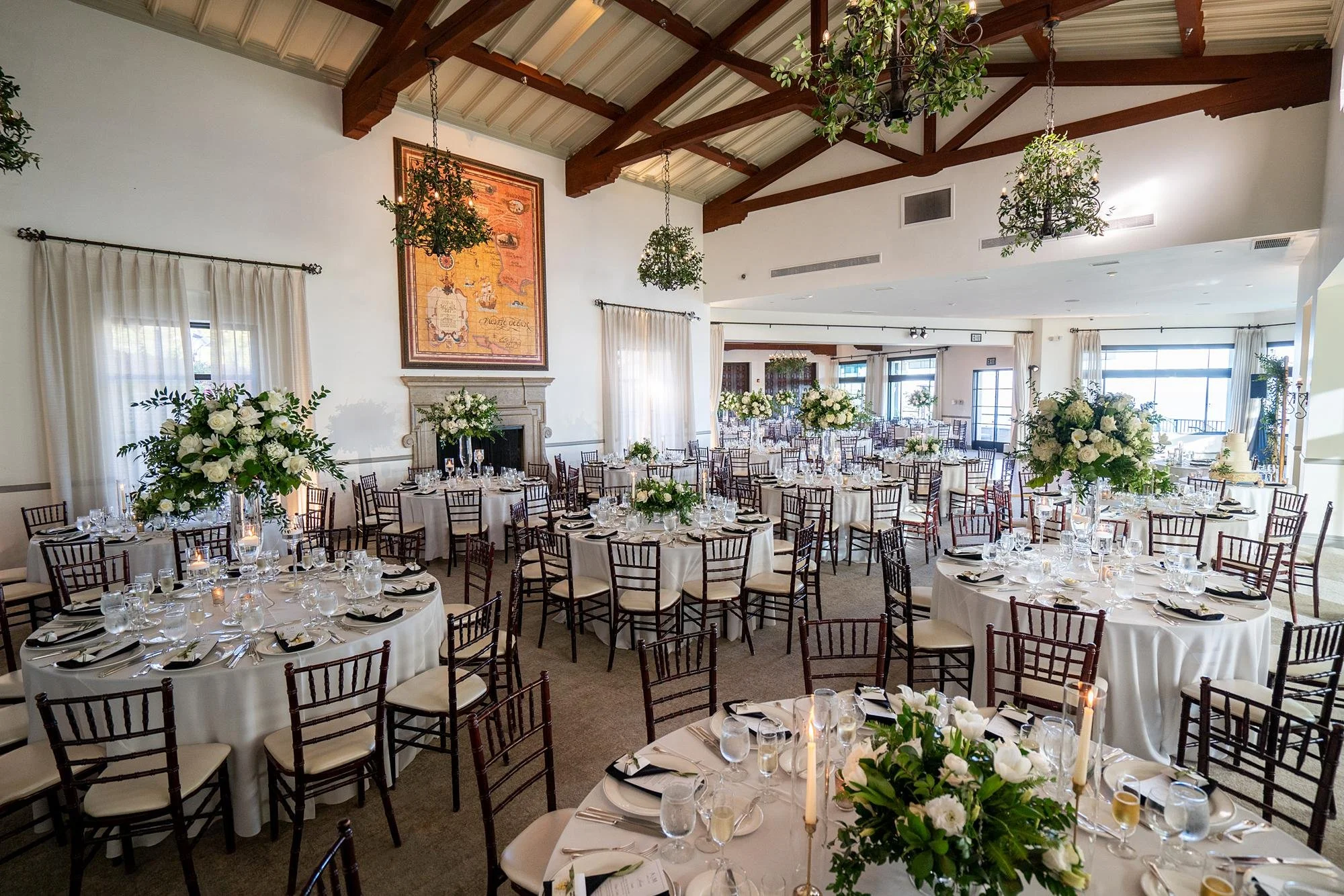 Wide view of Dining Room wedding reception with white florals and greenery at Bel Air Bay Club