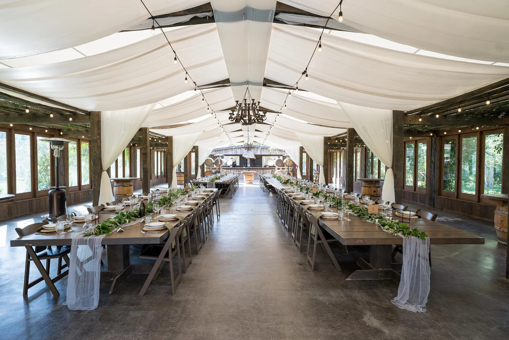 Wedding reception in the Pavilion at La Arboleda with long wooden tables and white fabric runners